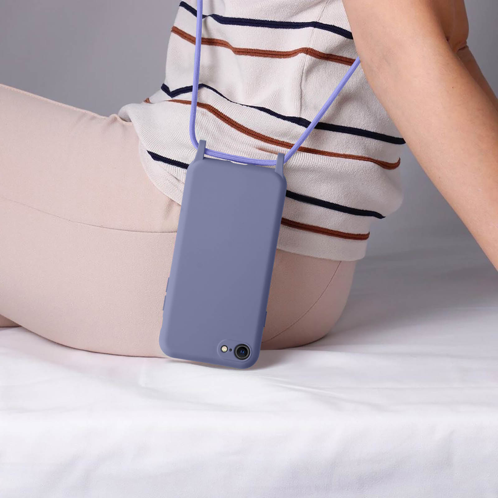 Une personne portant un cordon violet tenant un étui de téléphone violet avec un téléphone.