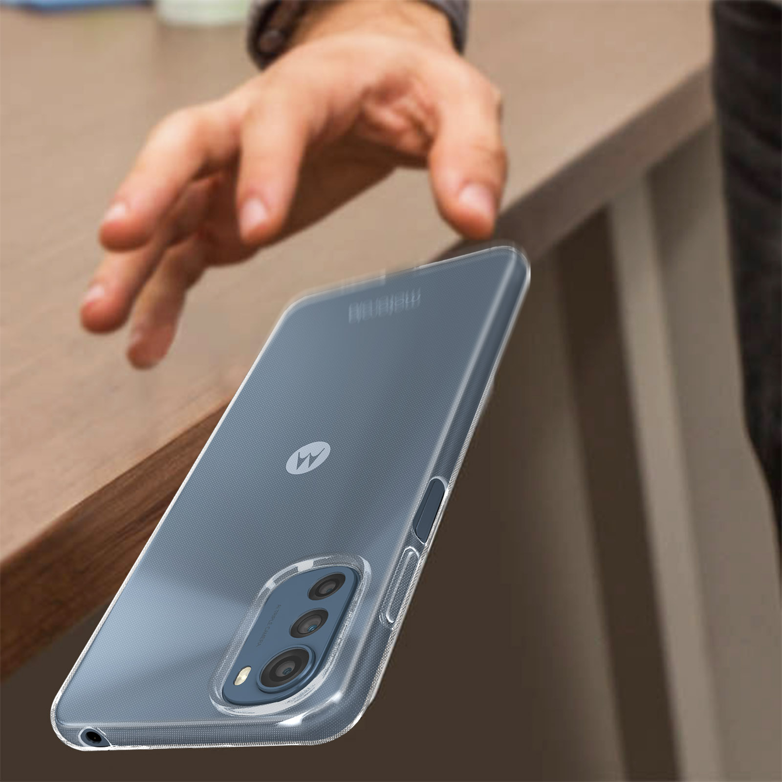 La mano di una persona che si protende verso un telefono in una custodia. Telefono su un tavolo, mano sfocata.