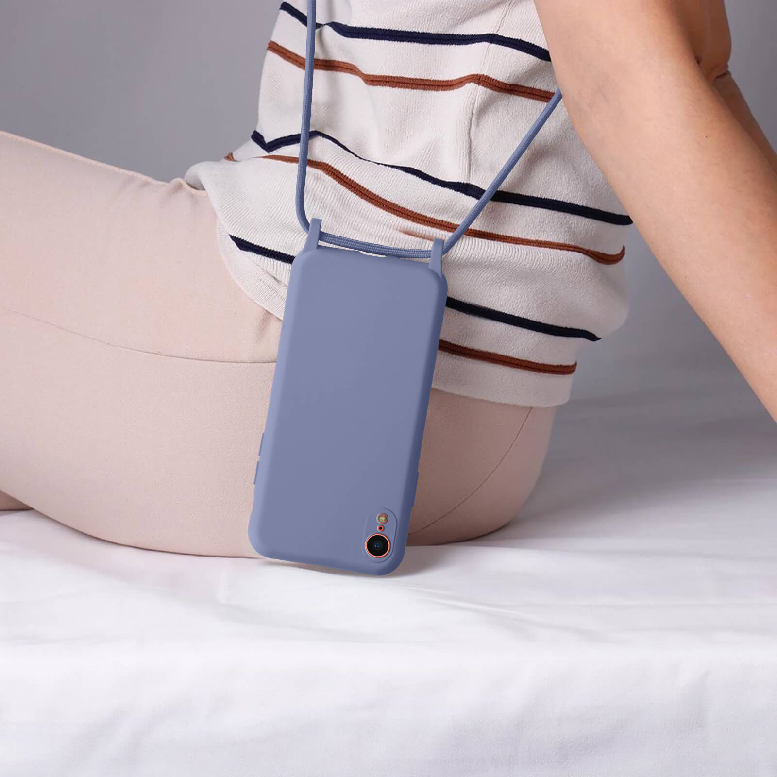 Personne portant un étui de téléphone avec une lanière. Le téléphone est bleu.