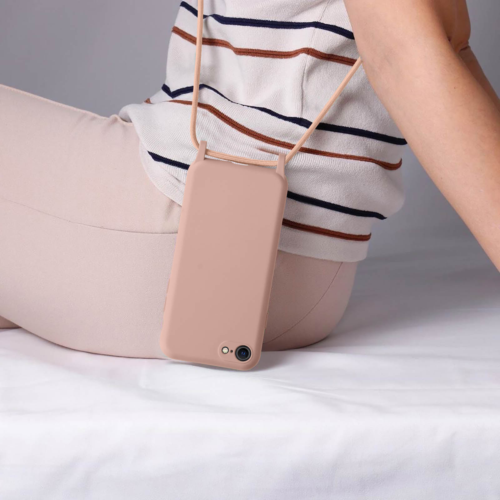 Femme avec une coque de téléphone avec une sangle. Le téléphone est rose.