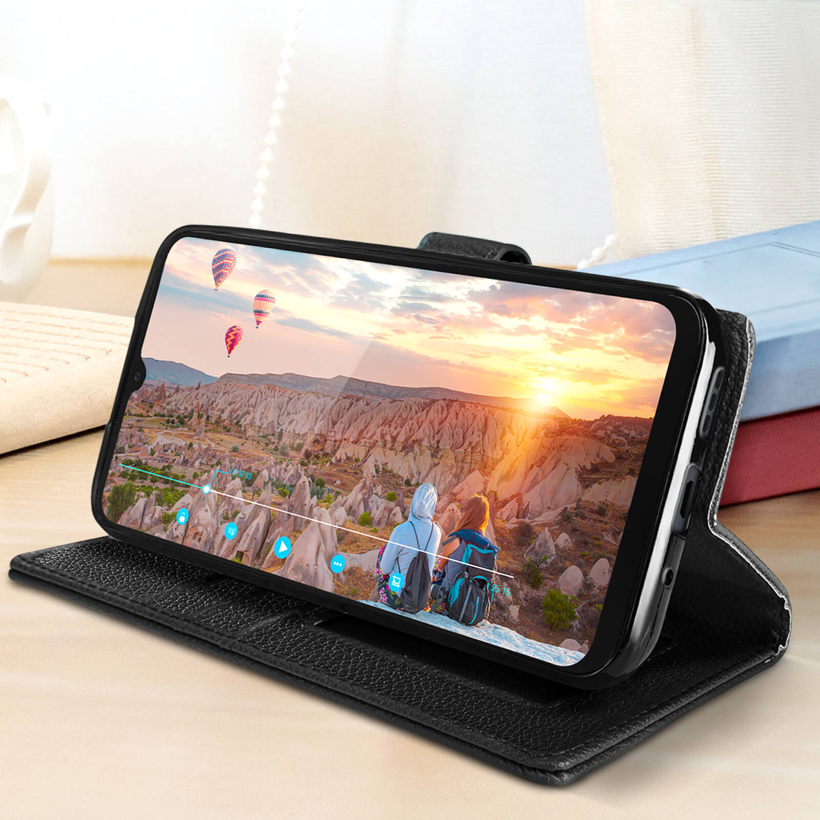 Smartphone in custodia a portafoglio nera, con tramonto e mongolfiere.