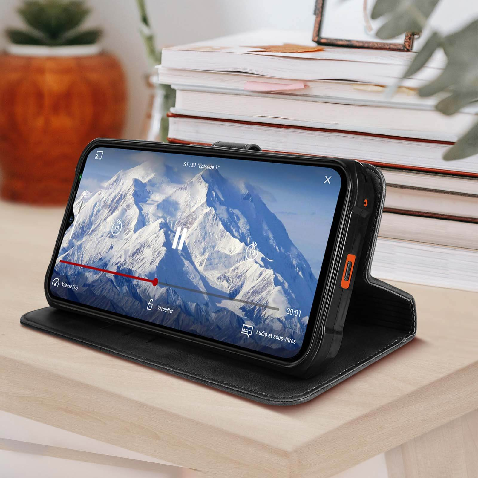 Telefono nero in una custodia, aperto su un tavolo di legno, che mostra un video di montagne innevate.