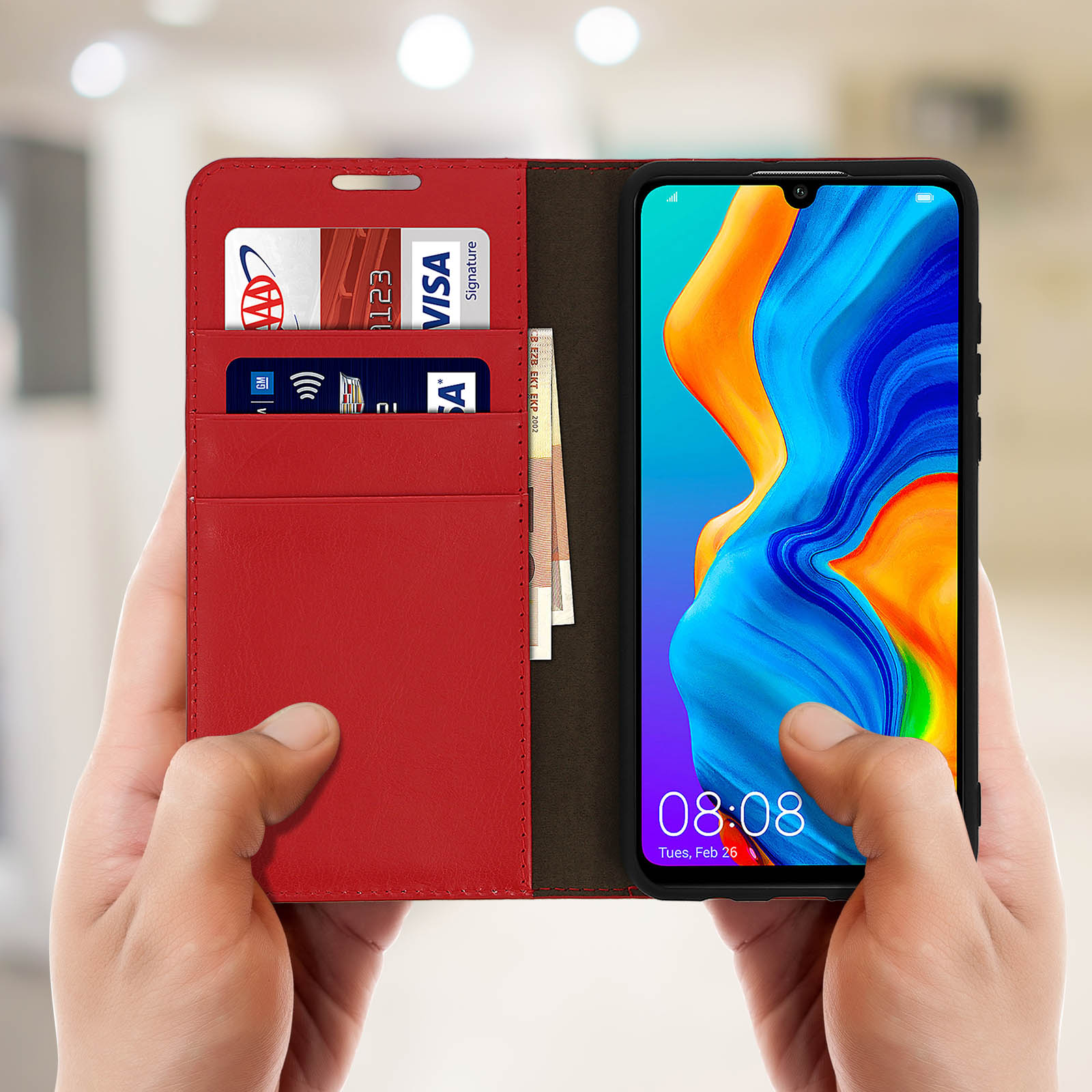 Le mani tengono una custodia a libro rossa per telefono. Ci sono carte e denaro all'interno della custodia.