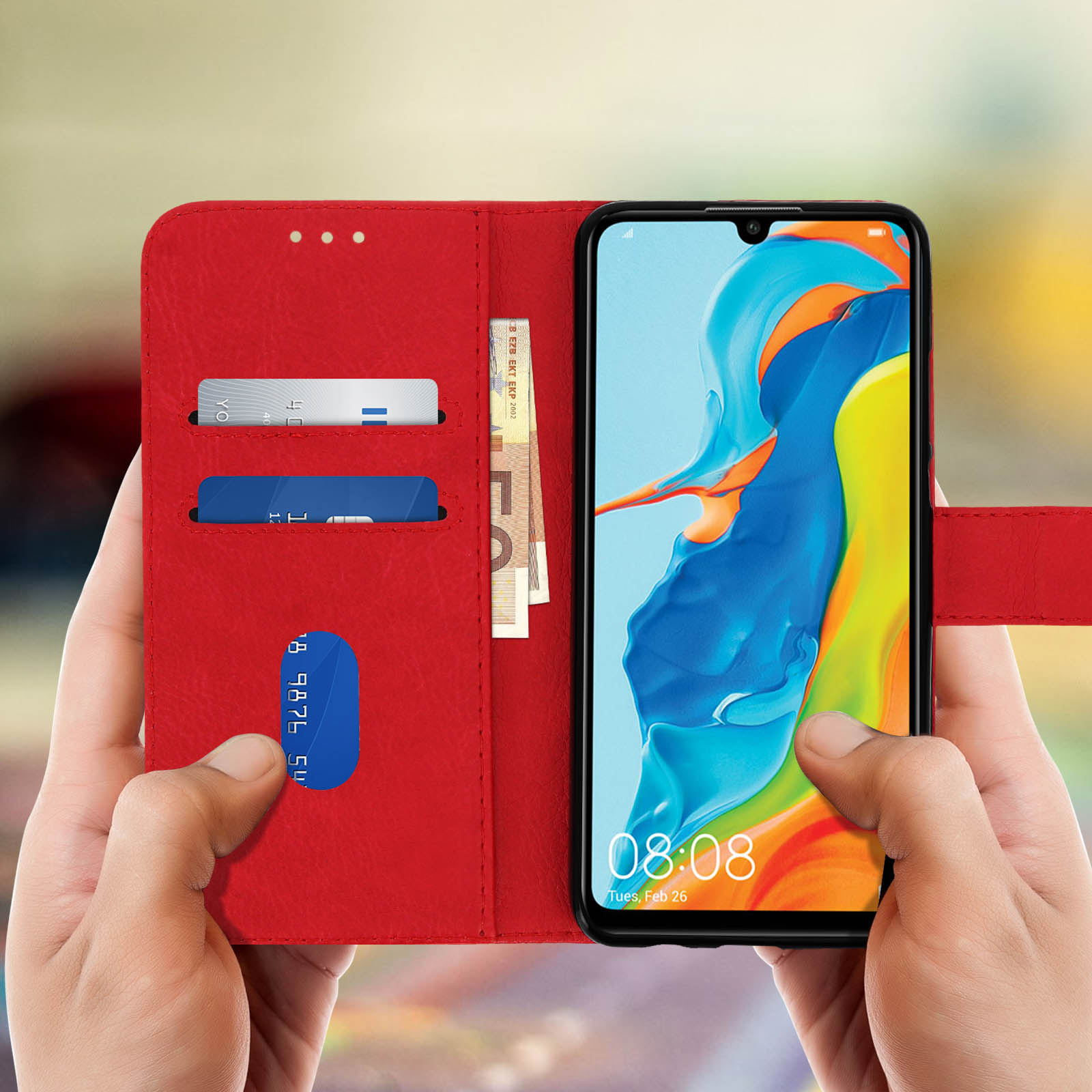 Mani che tengono aperta una custodia rossa. All'interno, carte e denaro. Schermo del telefono acceso.