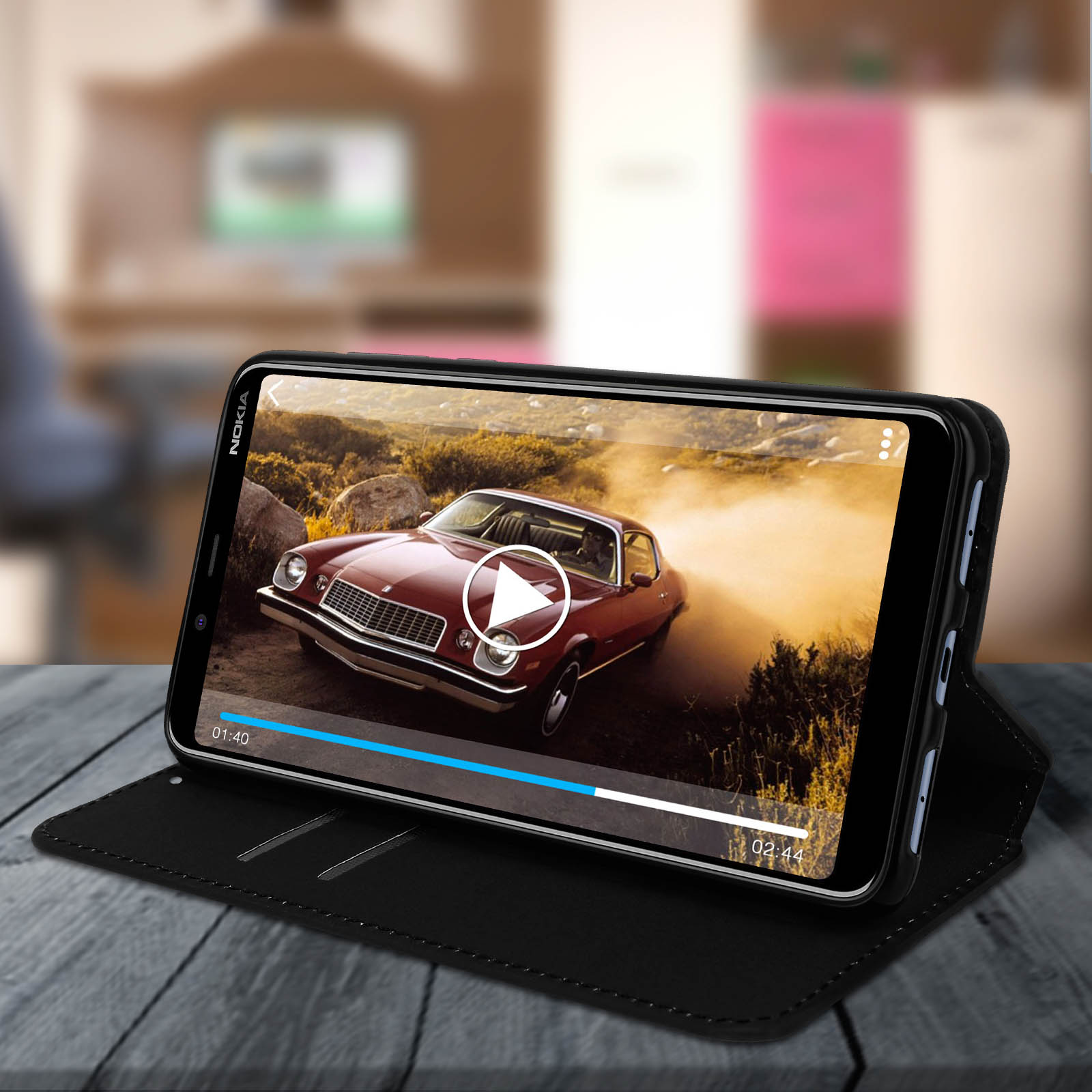 Un telefono che riproduce un video. È in una custodia nera aperta e su un tavolo.