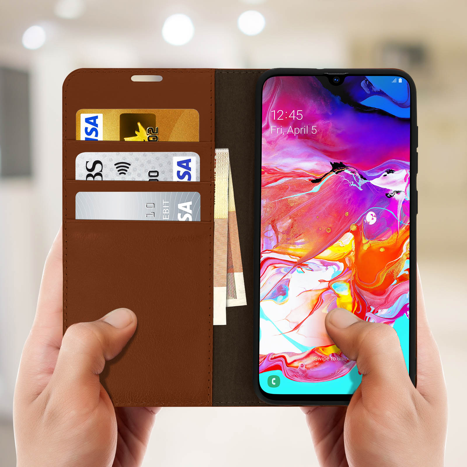 Mani che tengono una custodia marrone con telefono, carte e contanti.
