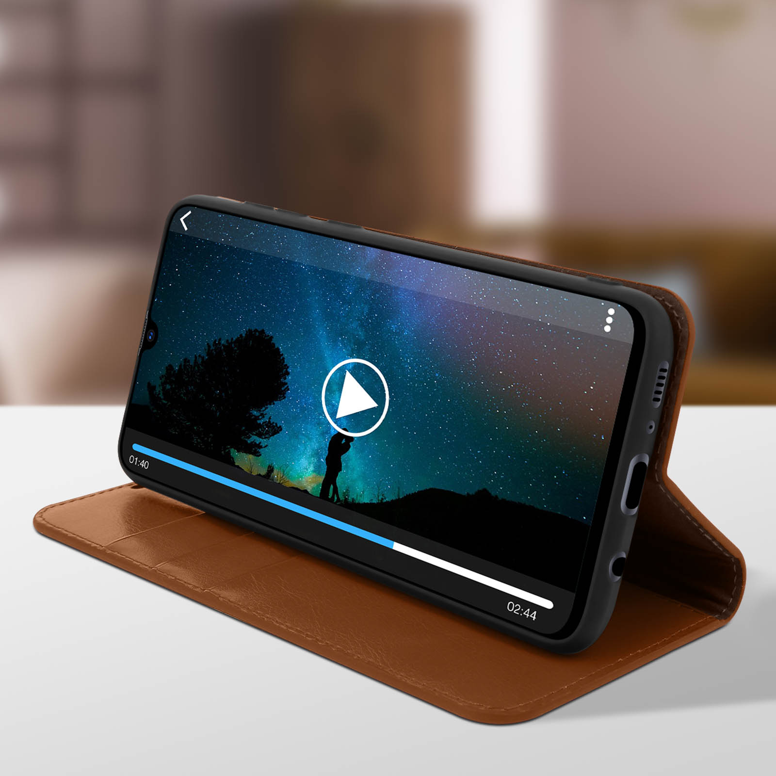 Un telefono in una custodia marrone riproduce un video. Lo schermo mostra un cielo notturno e una silhouette.