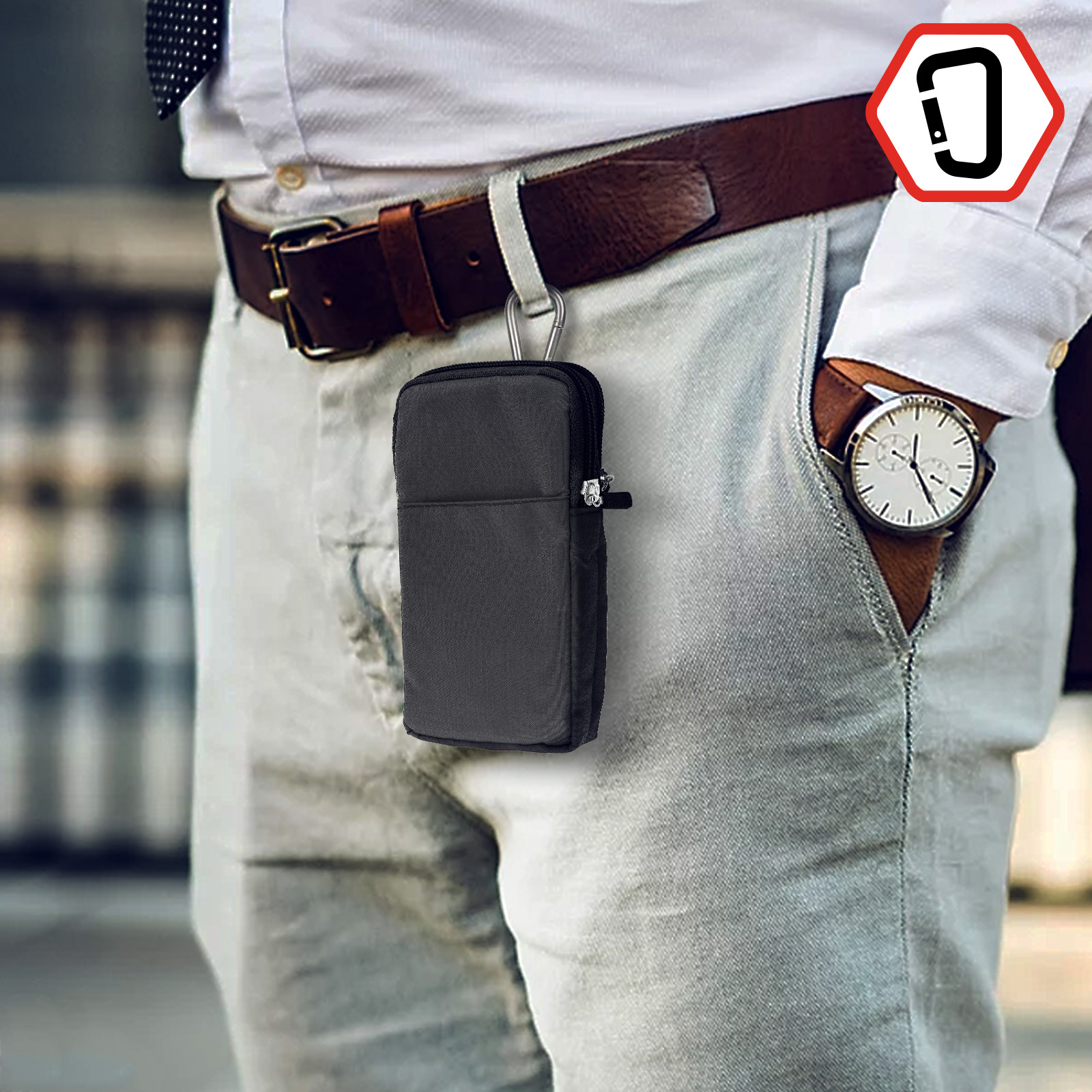 Mano di una persona che tiene una custodia nera collegata a una cintura. Sfondo pantaloni grigi.