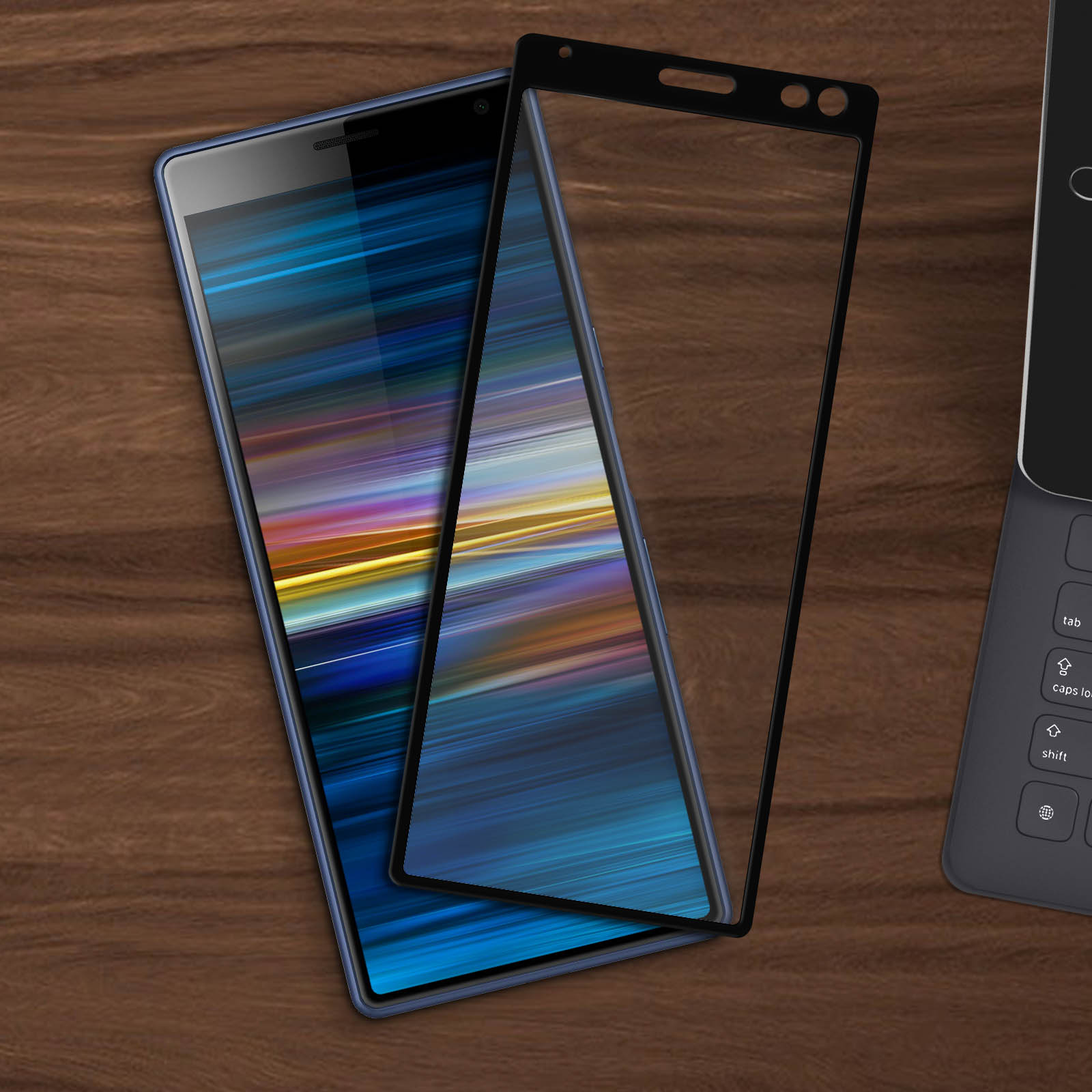 Due smartphone con protezioni schermo su una superficie di legno. Lo schermo di un telefono è acceso, mostrando linee colorate.