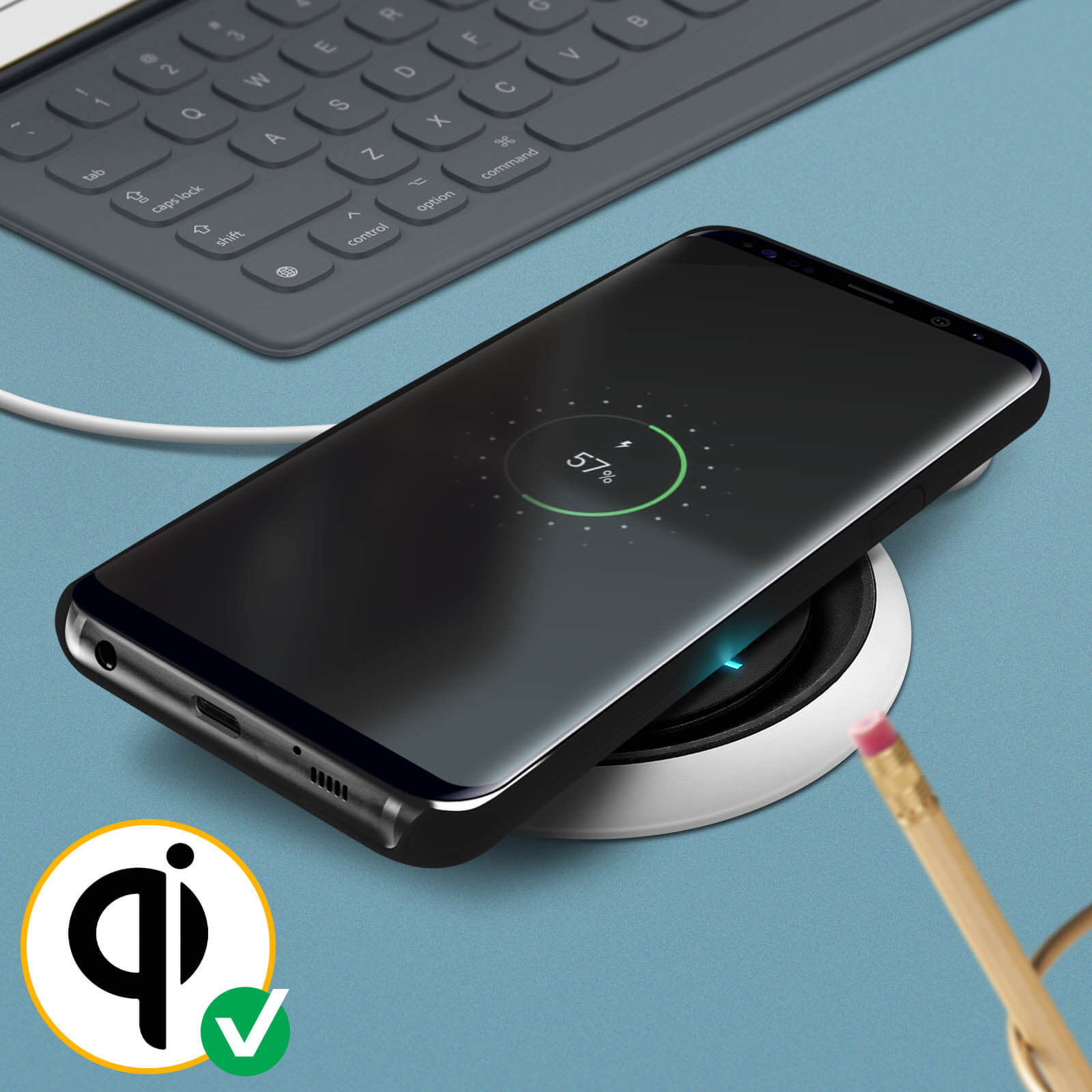 Un telefono nero su un caricatore wireless. Il telefono mostra il 57% di carica. Tastiera sullo sfondo.