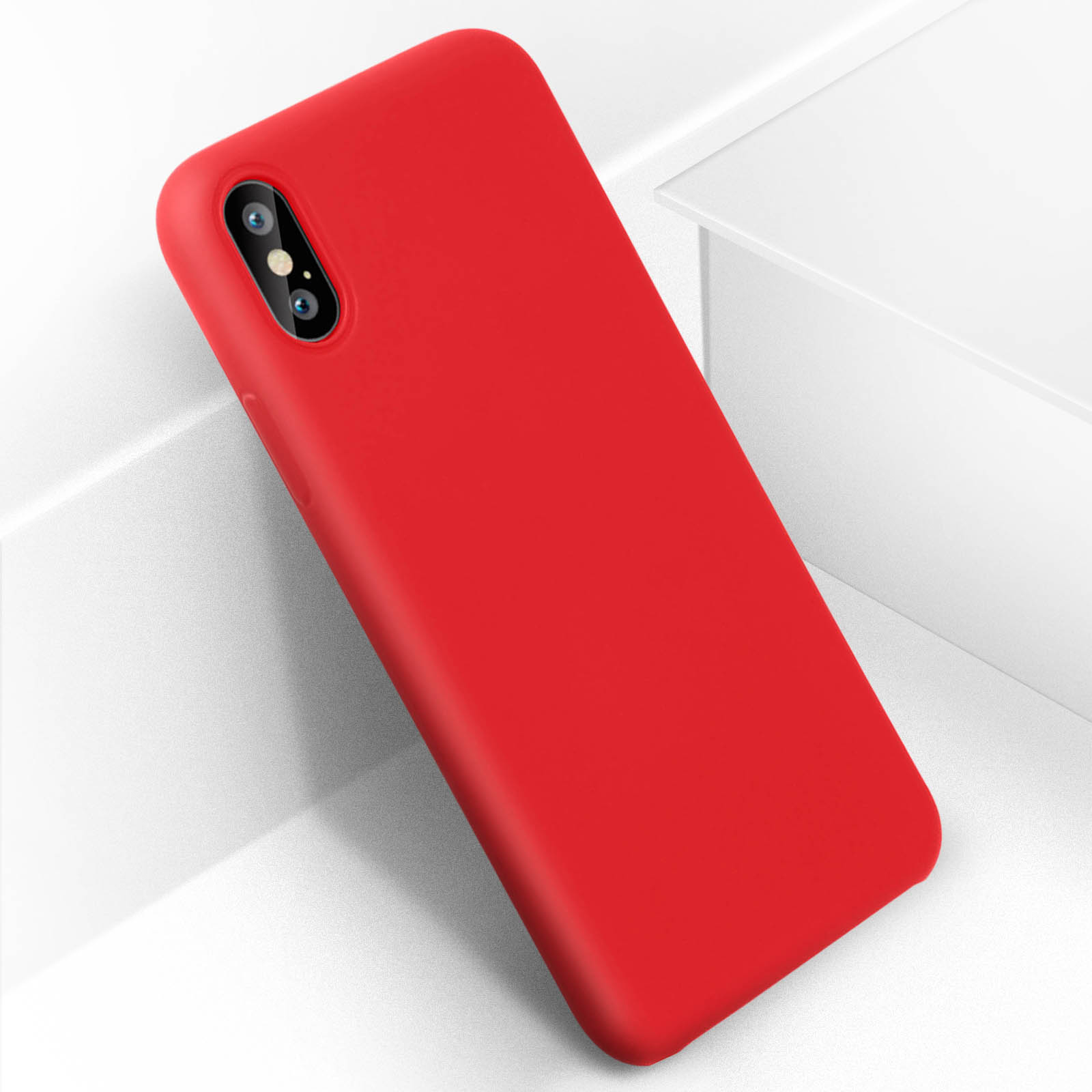 Un telefono rosso in una custodia è appoggiato a una superficie bianca. Il telefono ha una fotocamera.