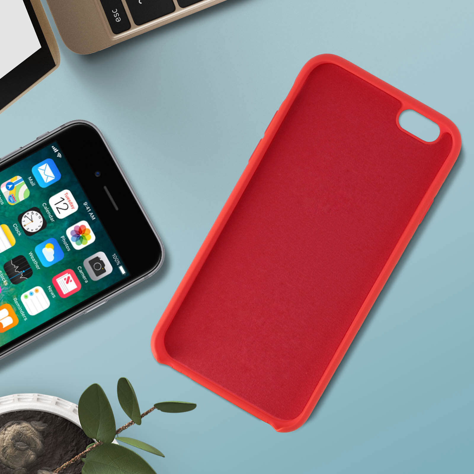 iPhone et une coque de téléphone rouge, avec une plante verte et un clavier à proximité.