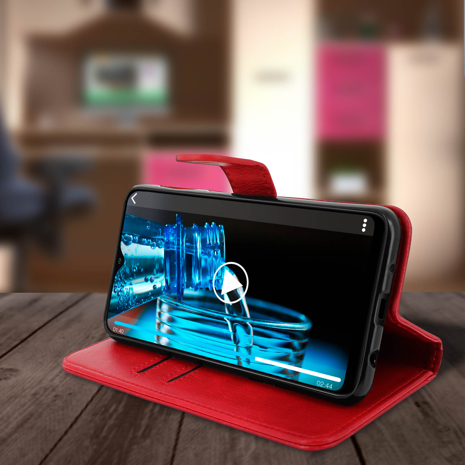 Telefoon in rode hoes speelt video af, op een houten bureau. Vage achtergrond.