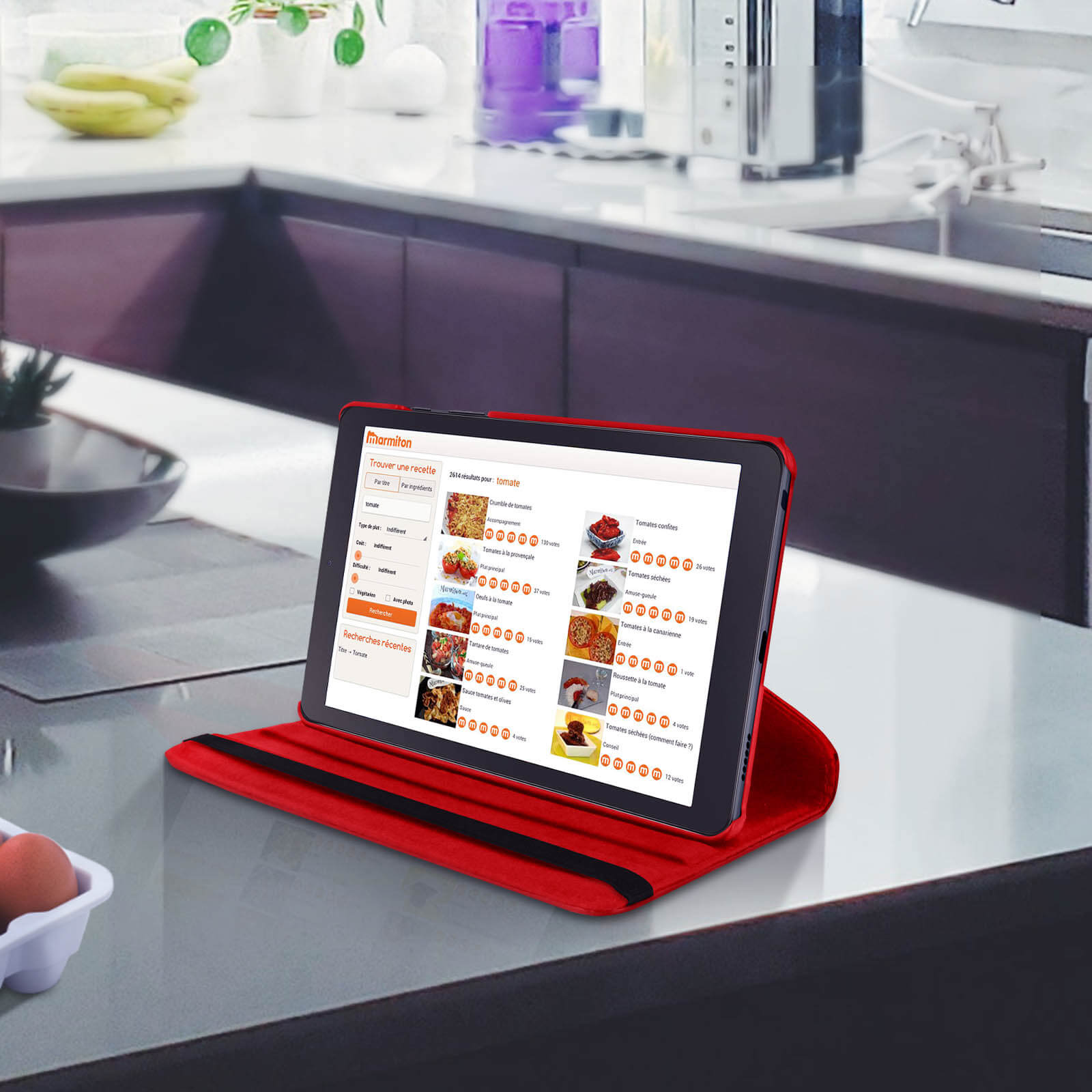 Un tablet in una cover rossa che mostra un sito web di ricette su un piano di lavoro della cucina.