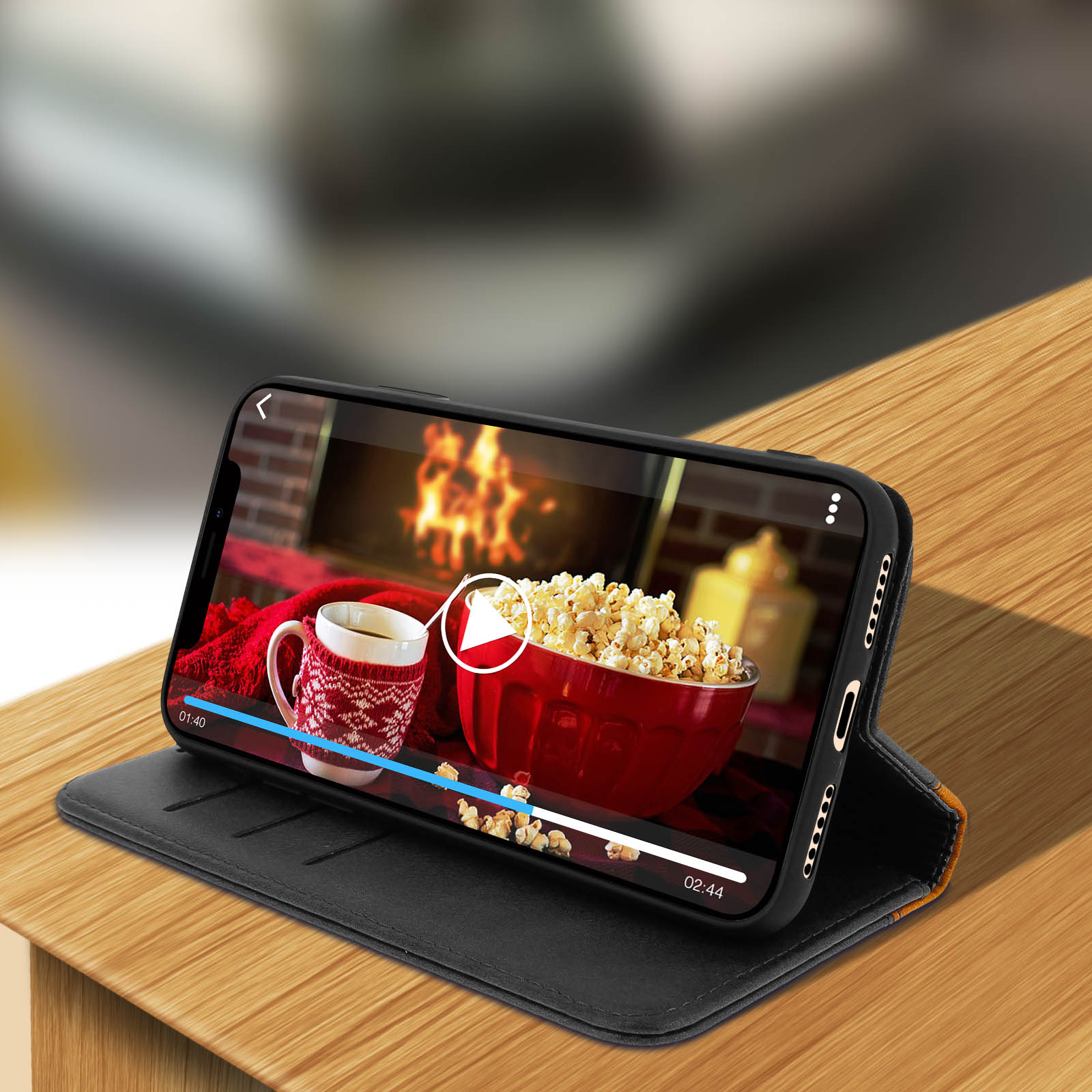 Un telefono in una custodia nera mostra un video con popcorn e una bevanda su una superficie di legno.