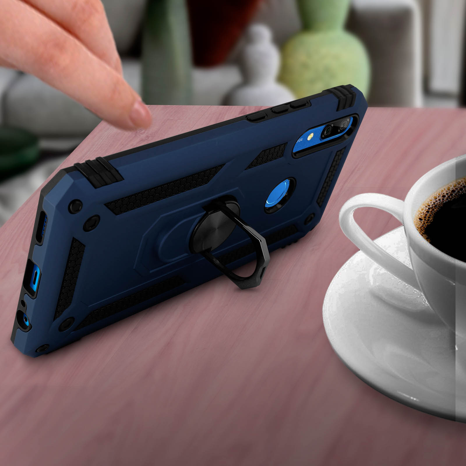 Telefoonhoes op een tafel. Een koffiekopje, een hand en een effen achtergrond zijn zichtbaar.