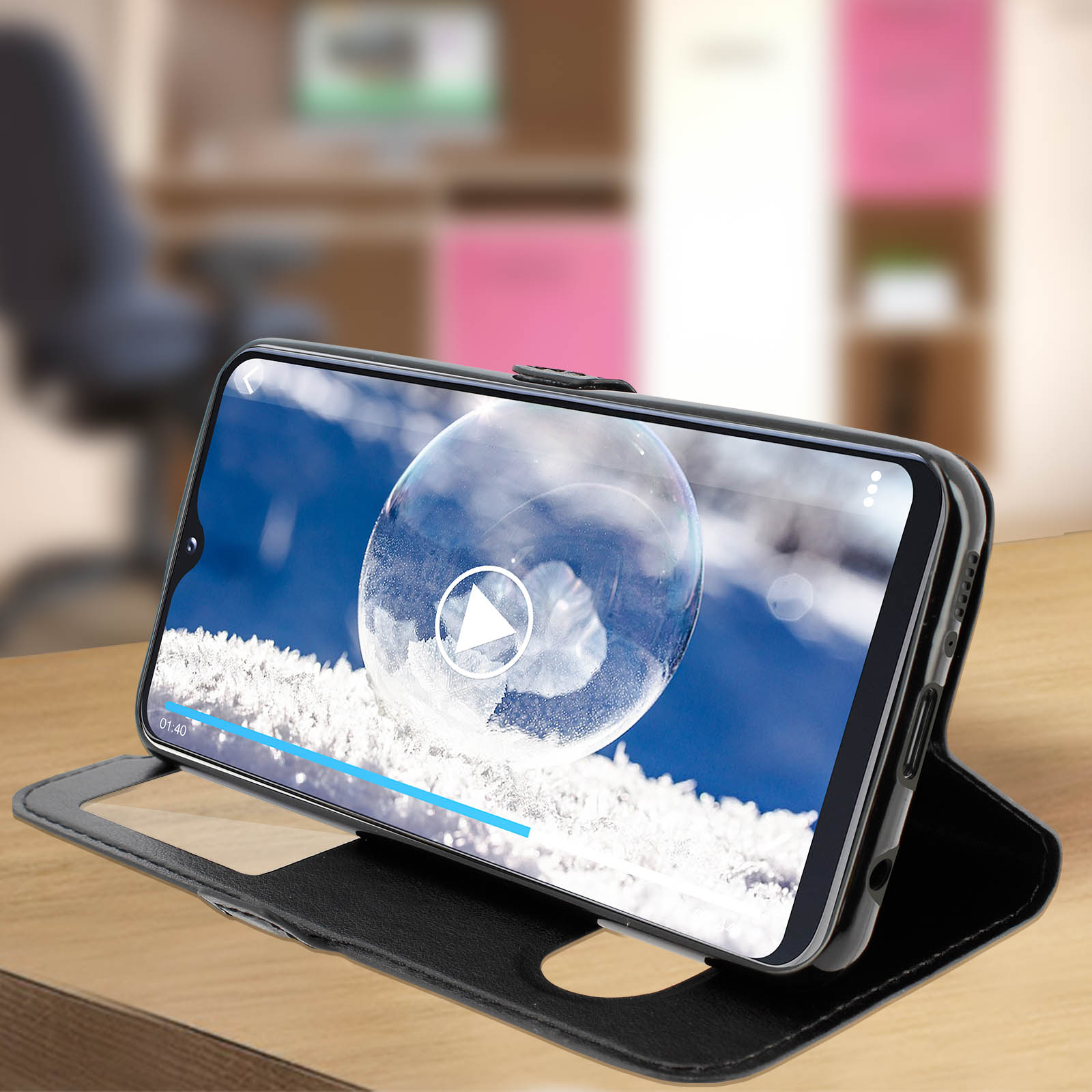 Custodia per telefono con un telefono che riproduce un video con una bolla. La custodia è aperta su un tavolo di legno.