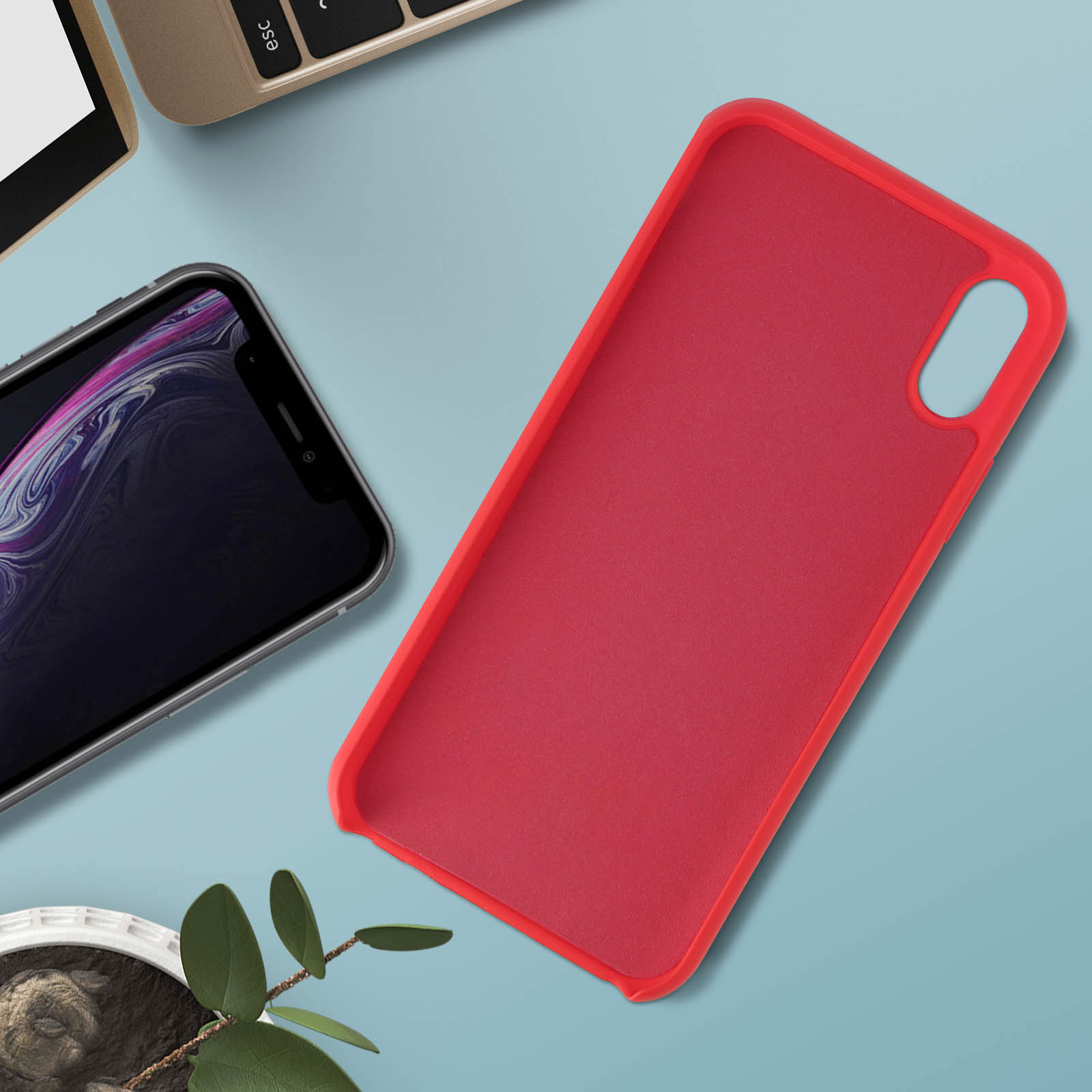 Une coque de téléphone rouge sur une table avec un smartphone et des feuilles. Vue de dessus.