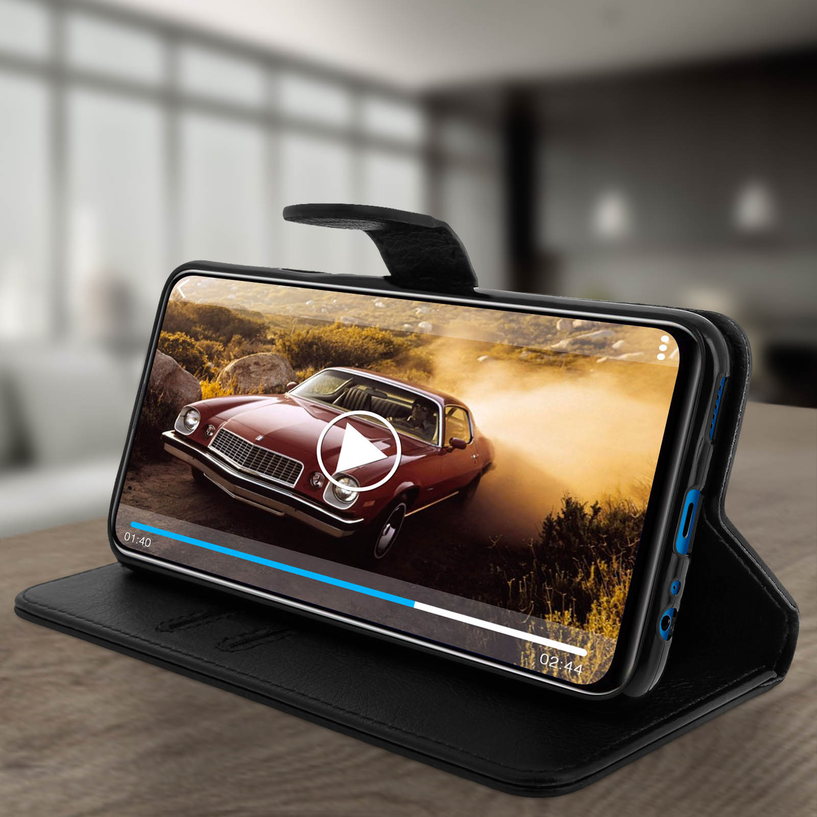 Coque noire affichant une vidéo de voiture, sur une table marron.