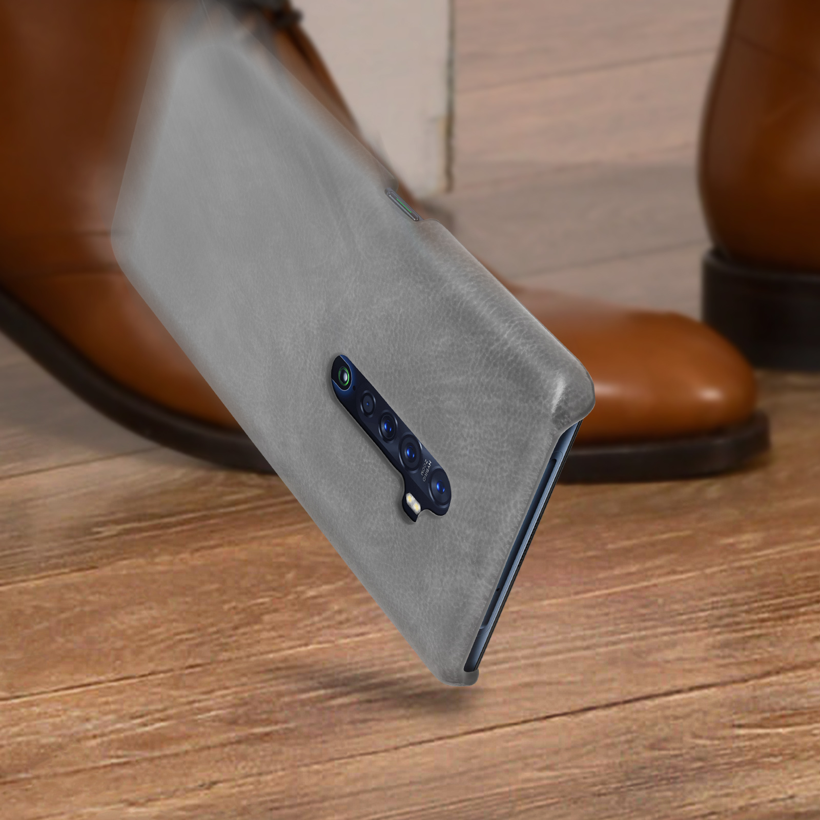 Una custodia grigia per telefono è vicino a scarpe marroni su una superficie di legno.