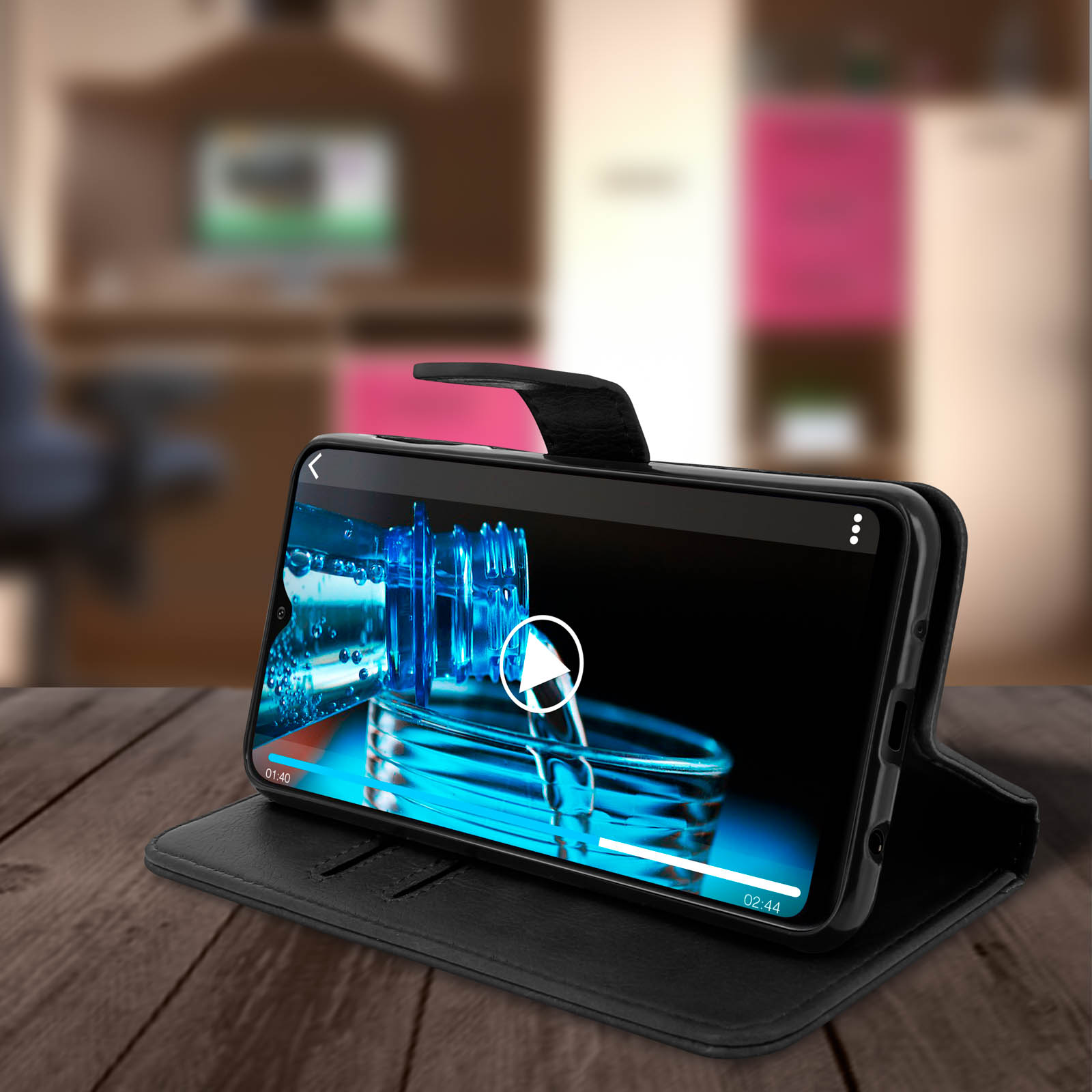 Téléphone dans un étui noir sur une table en bois. Vidéo en cours. Fond sombre avec une pièce.