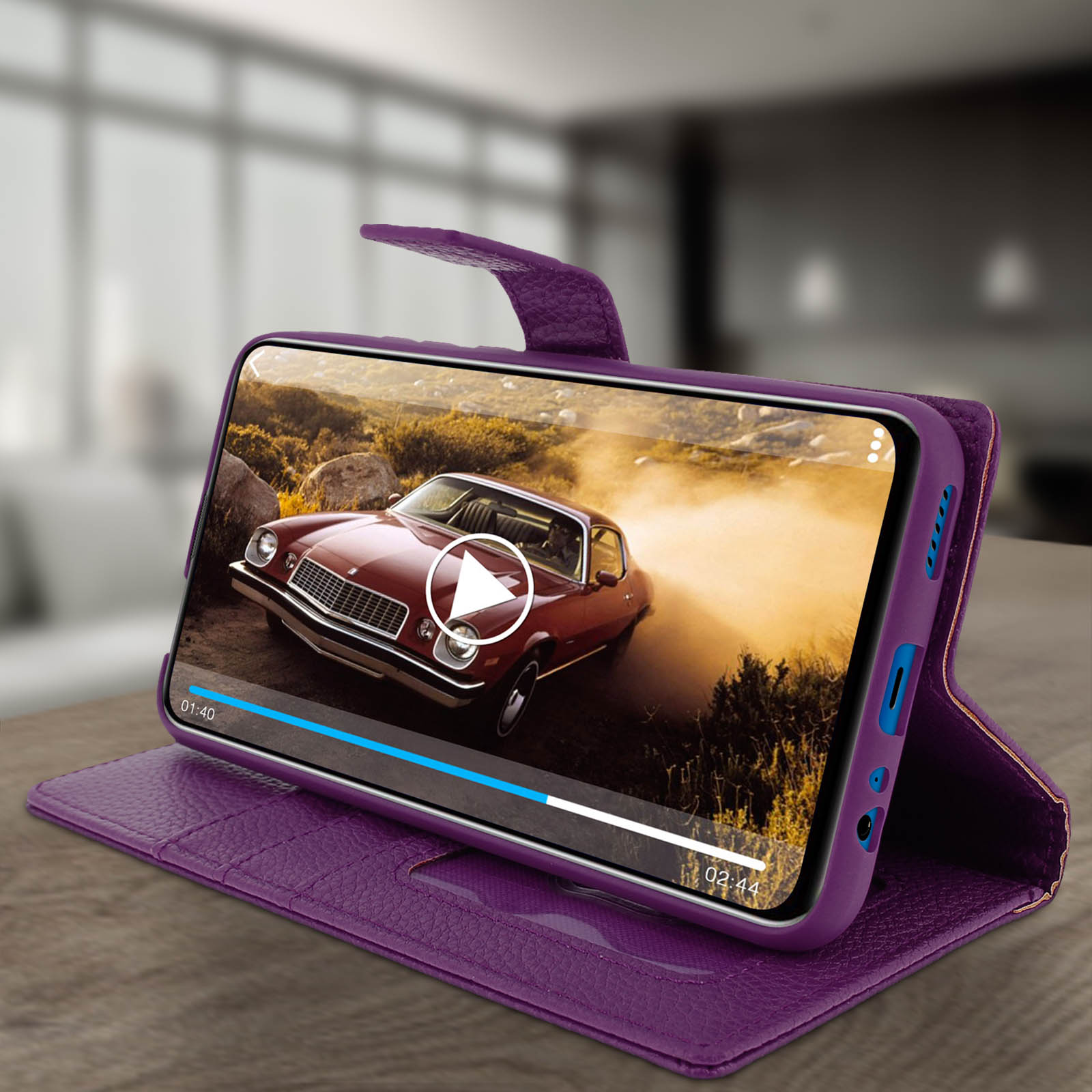 Un telefono che mostra un video di auto in una custodia viola. È aperto su un tavolo. Pulsante di riproduzione sullo schermo.