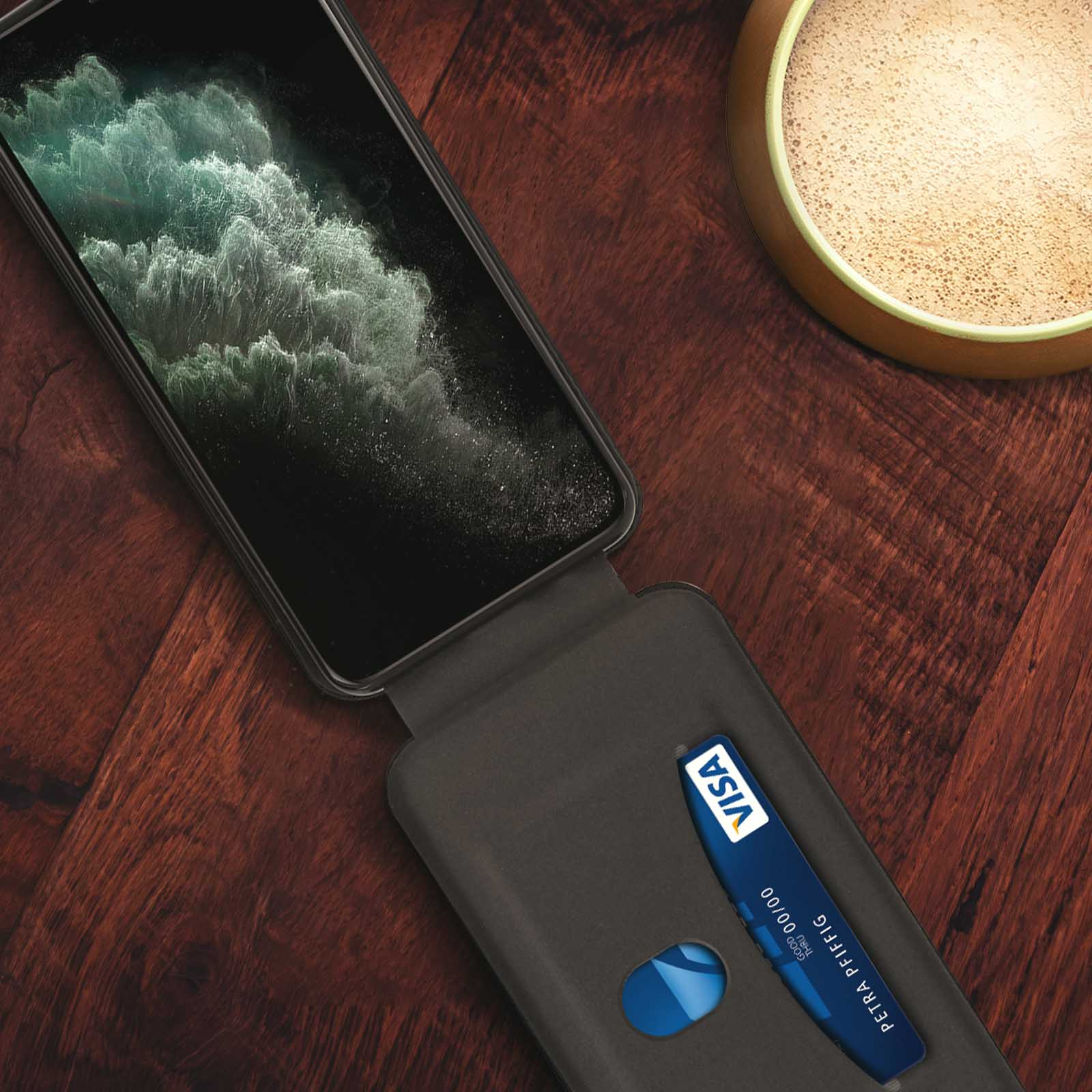 Un telefono in una custodia con una carta Visa all'interno, su un tavolo di legno.