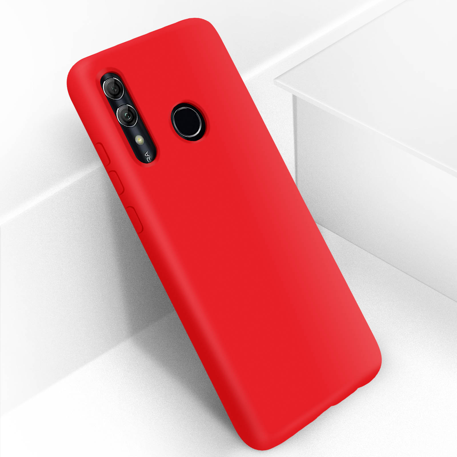 Coque de téléphone rouge inclinée sur une surface blanche. La coque a des découpes pour la caméra et le capteur.
