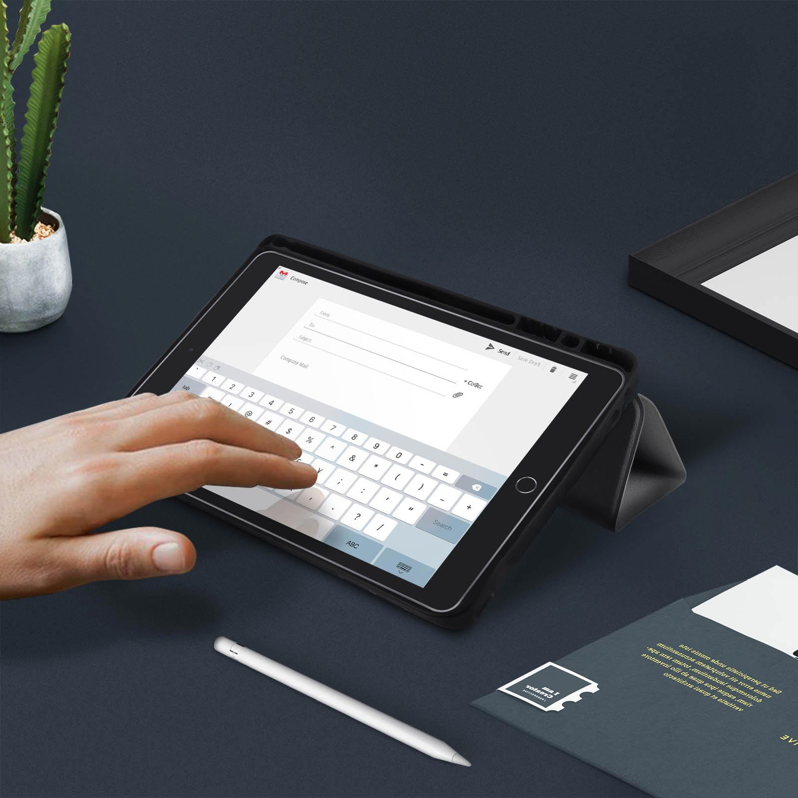 La mano di una persona che interagisce con un tablet con una tastiera sullo schermo. Uno stilo e dei fogli sono vicini.