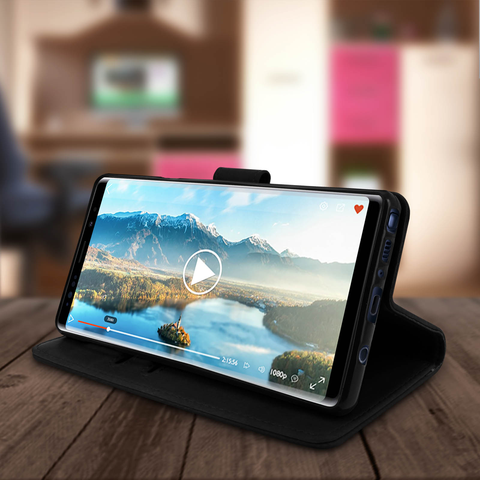 Téléphone dans un étui noir affichant une vidéo d'un lac, sur une table en bois dans un salon.