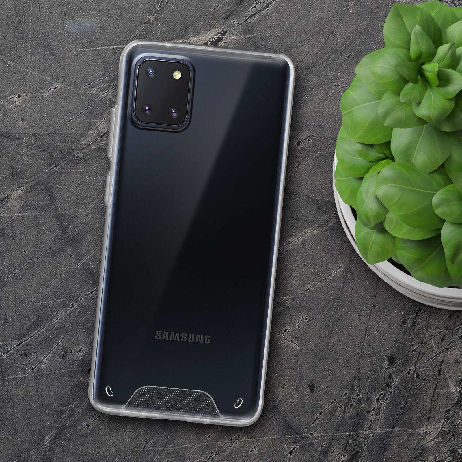 Custodia trasparente su un telefono. Una pianta in un vaso bianco è a destra del telefono.
