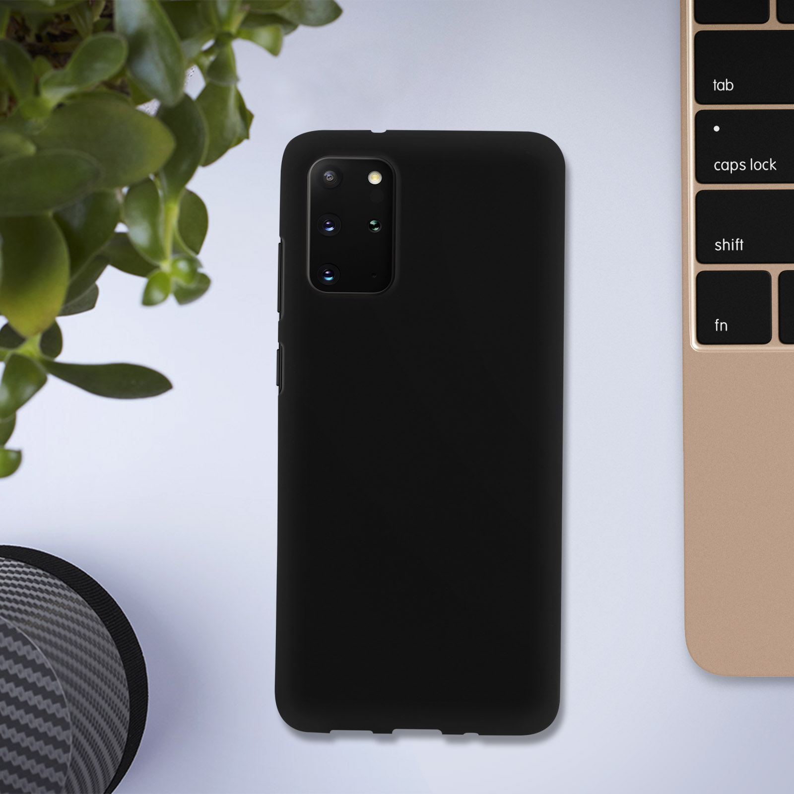 Une coque de téléphone noire sur une surface blanche à côté d'une petite plante et d'un clavier.