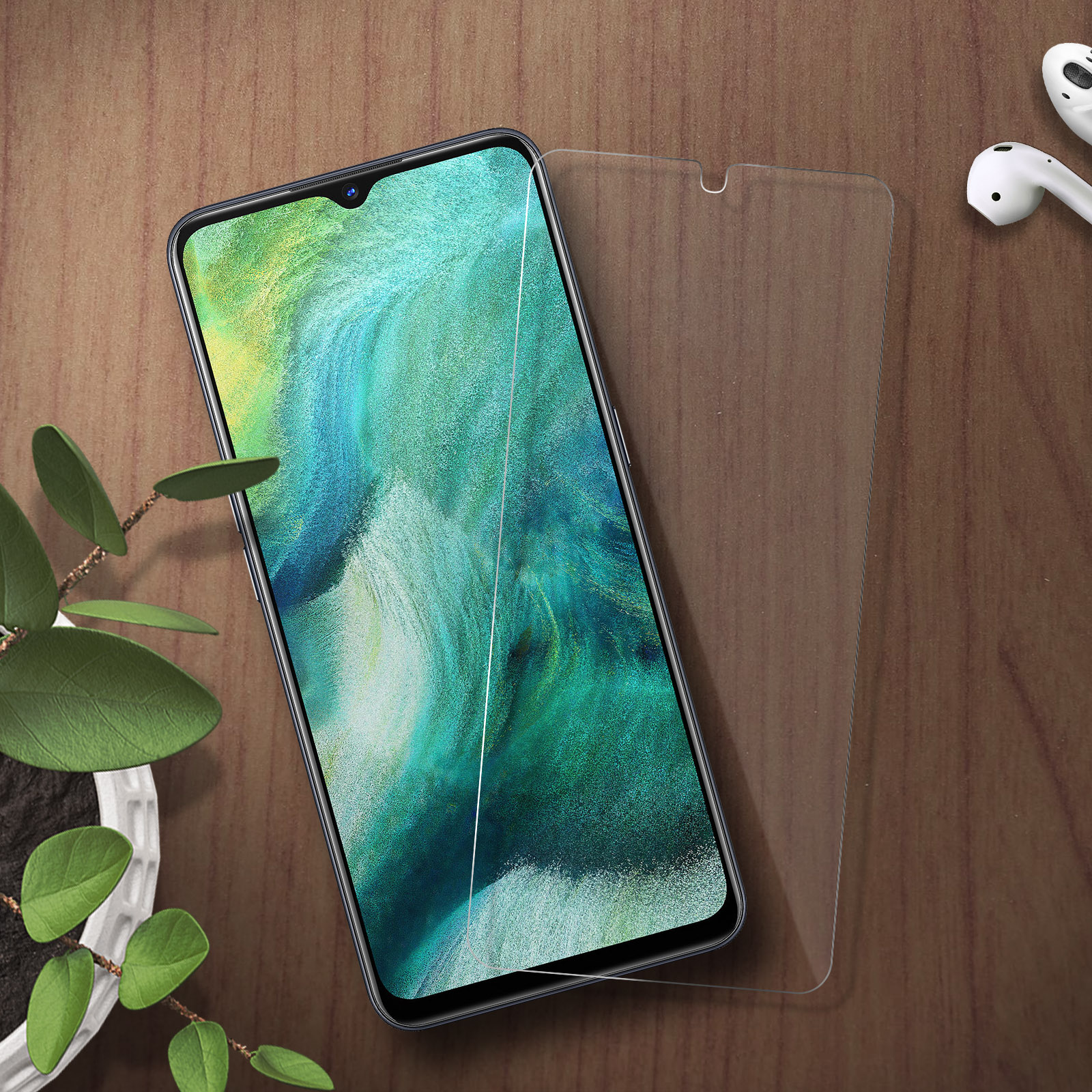 Un telefono e una protezione schermo su legno. Una piccola pianta e auricolari sono vicini.