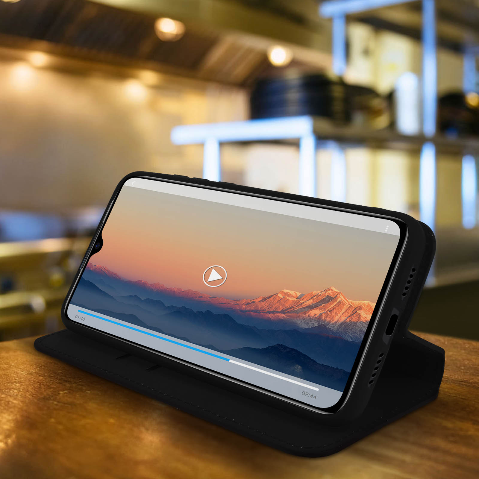 Un téléphone dans un étui noir montrant une vidéo sur une surface en bois.