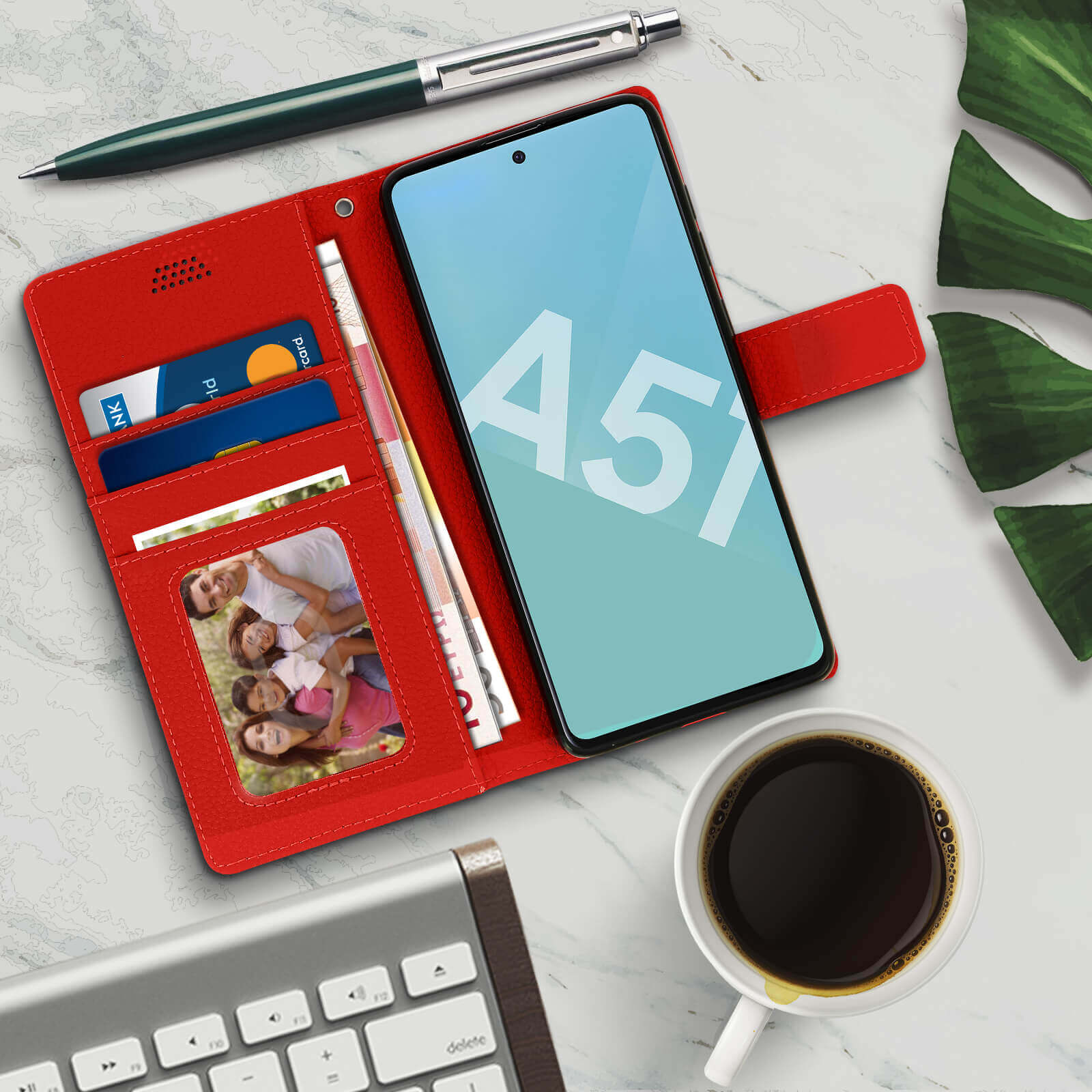 Coque de téléphone rouge avec cartes de crédit, stylo et photo de famille sur marbre.