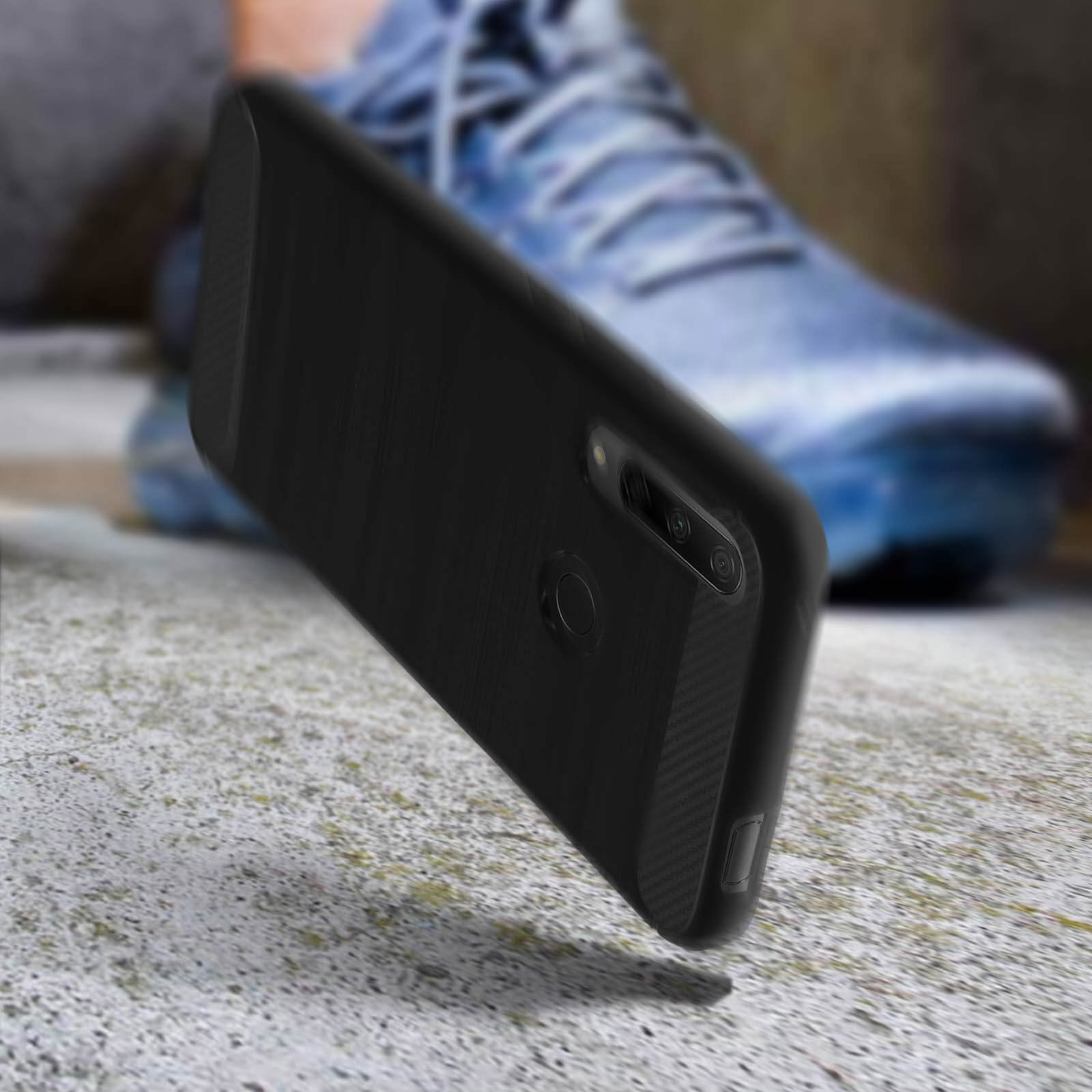 Zwarte telefoonhoes voor een wazige achtergrond. Sneakers zijn zichtbaar. De telefoon staat schuin.