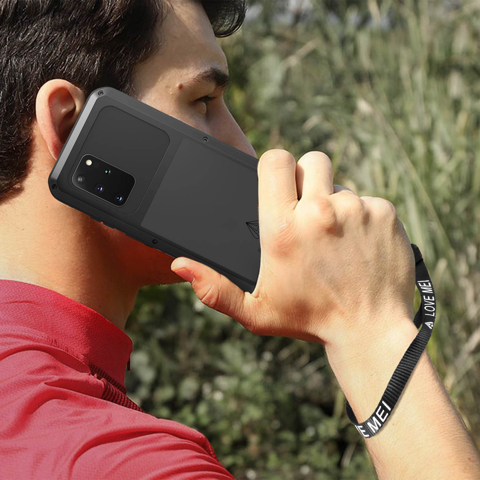 Uomo che tiene un telefono nero, indossa una camicia rossa. Cinturino nero visibile.