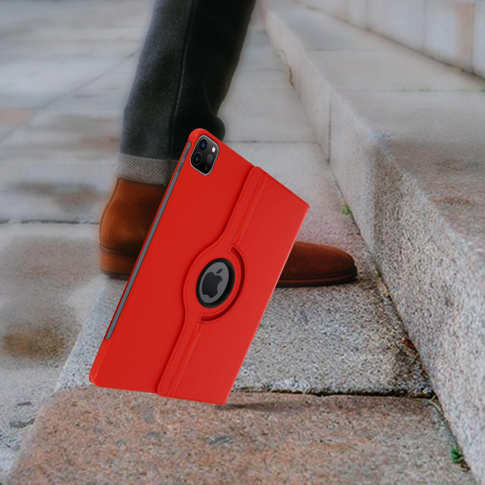 Custodia iPad rossa con rotazione, gamba/scarpa sullo sfondo, su gradini in pietra.