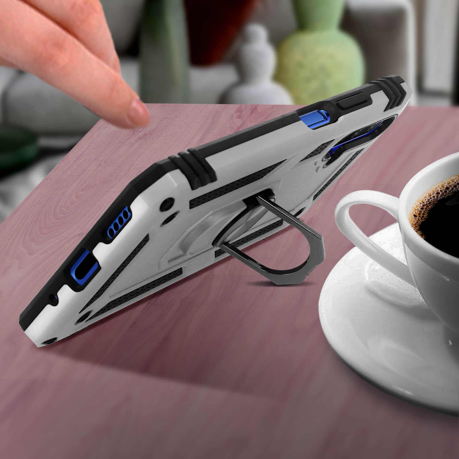 Custodia bianca e grigia con supporto, su tavolo di legno con tazza di caffè.