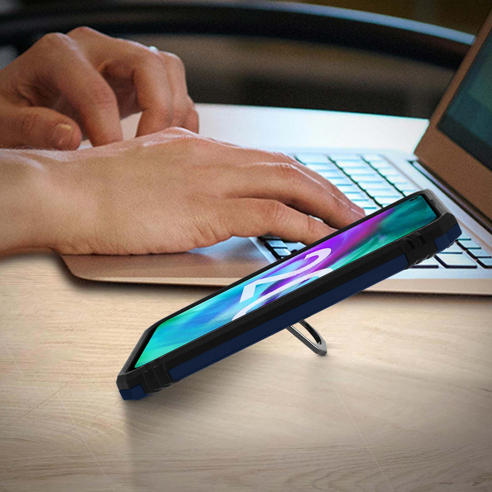 Téléphone dans un étui bleu surélevé. Mains d'une personne sur un ordinateur portable en arrière-plan.