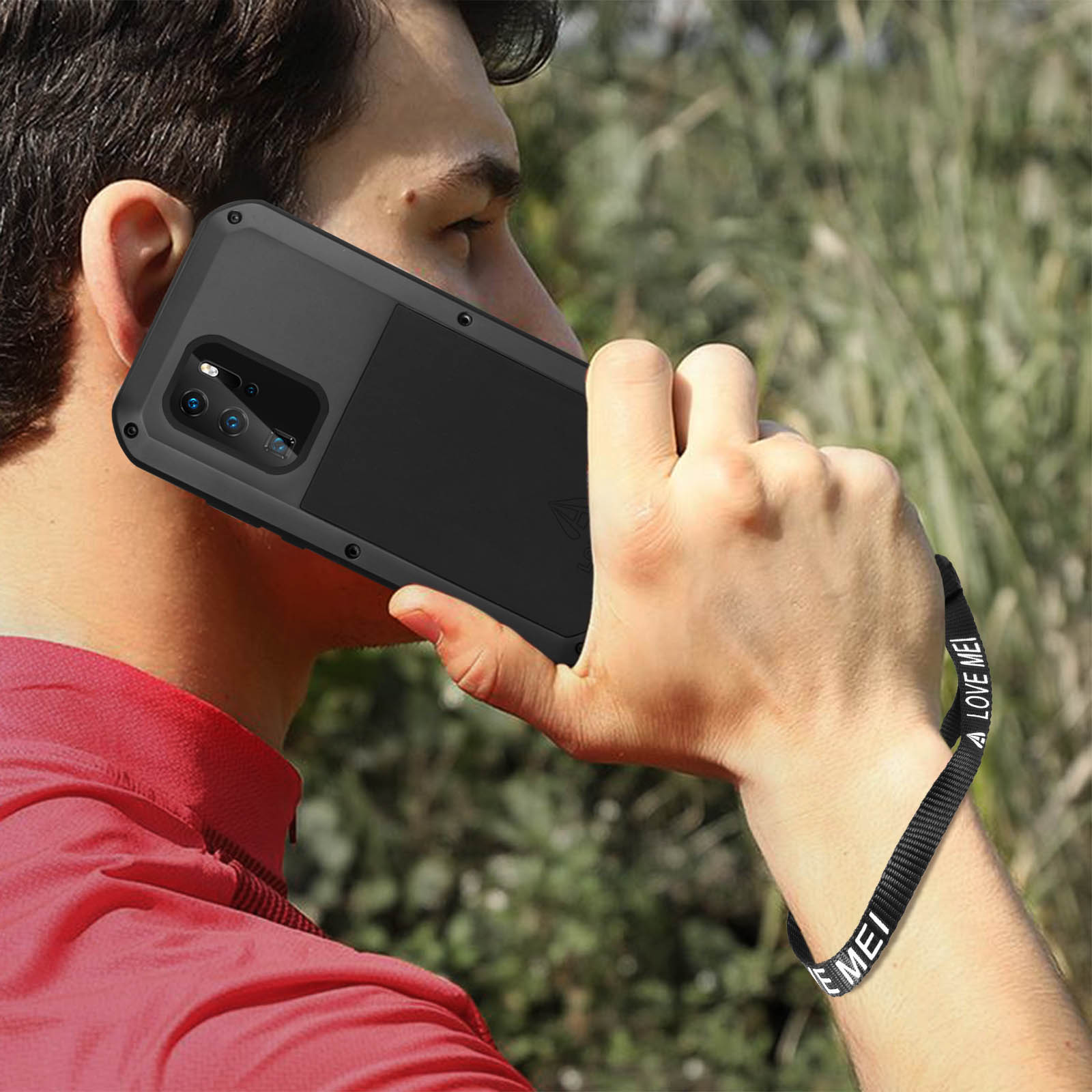 Uomo che tiene un telefono con custodia. Il telefono è nero. Sfondo verde.