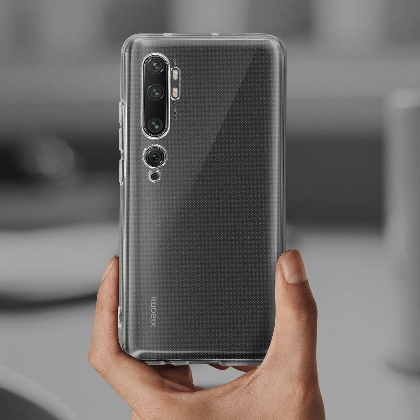 Una mano tiene una custodia trasparente per telefono. La custodia è attorno a un telefono con più fotocamere.