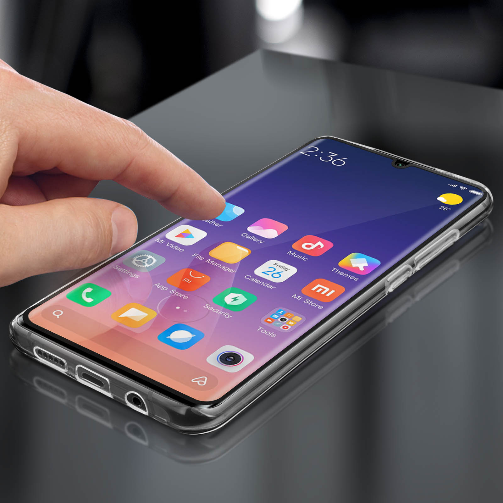 Mano che tocca lo schermo del telefono con icone delle app. Telefono in custodia trasparente su superficie riflettente.