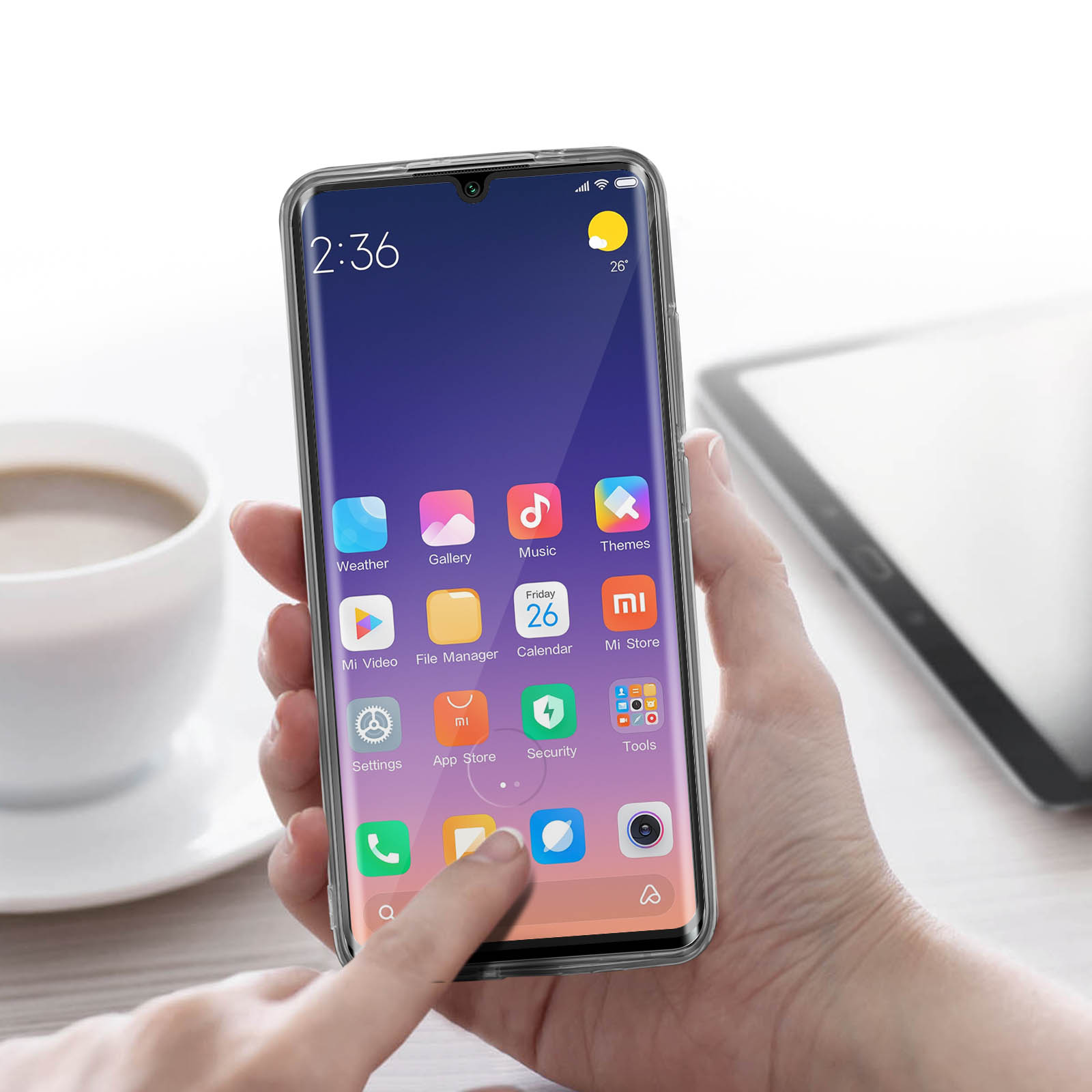 Persona che tiene in mano smartphone con custodia trasparente. Il telefono mostra icone. Tazza e tablet.