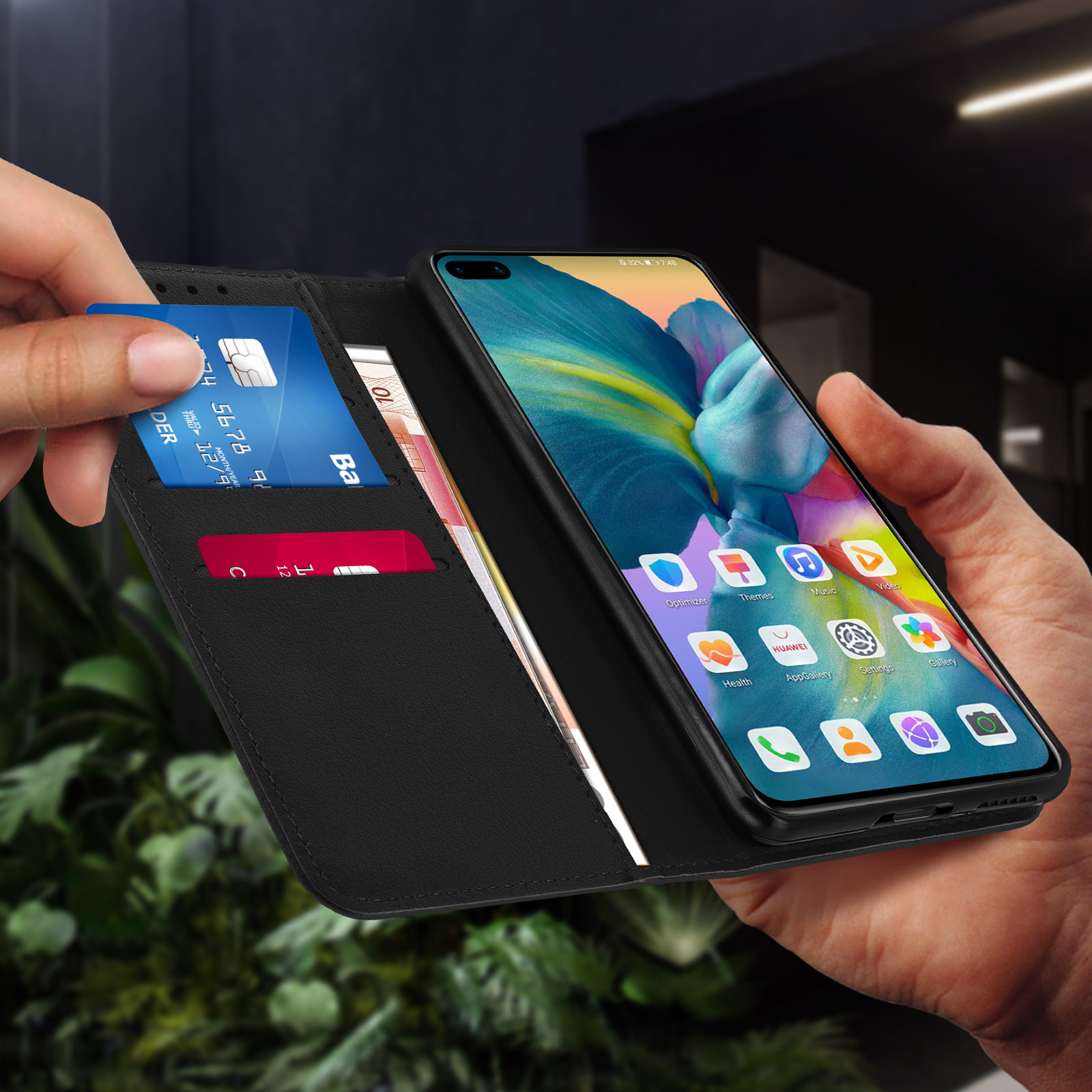 Mano che tiene un portafoglio per telefono nero con carta di credito e contanti all'interno.