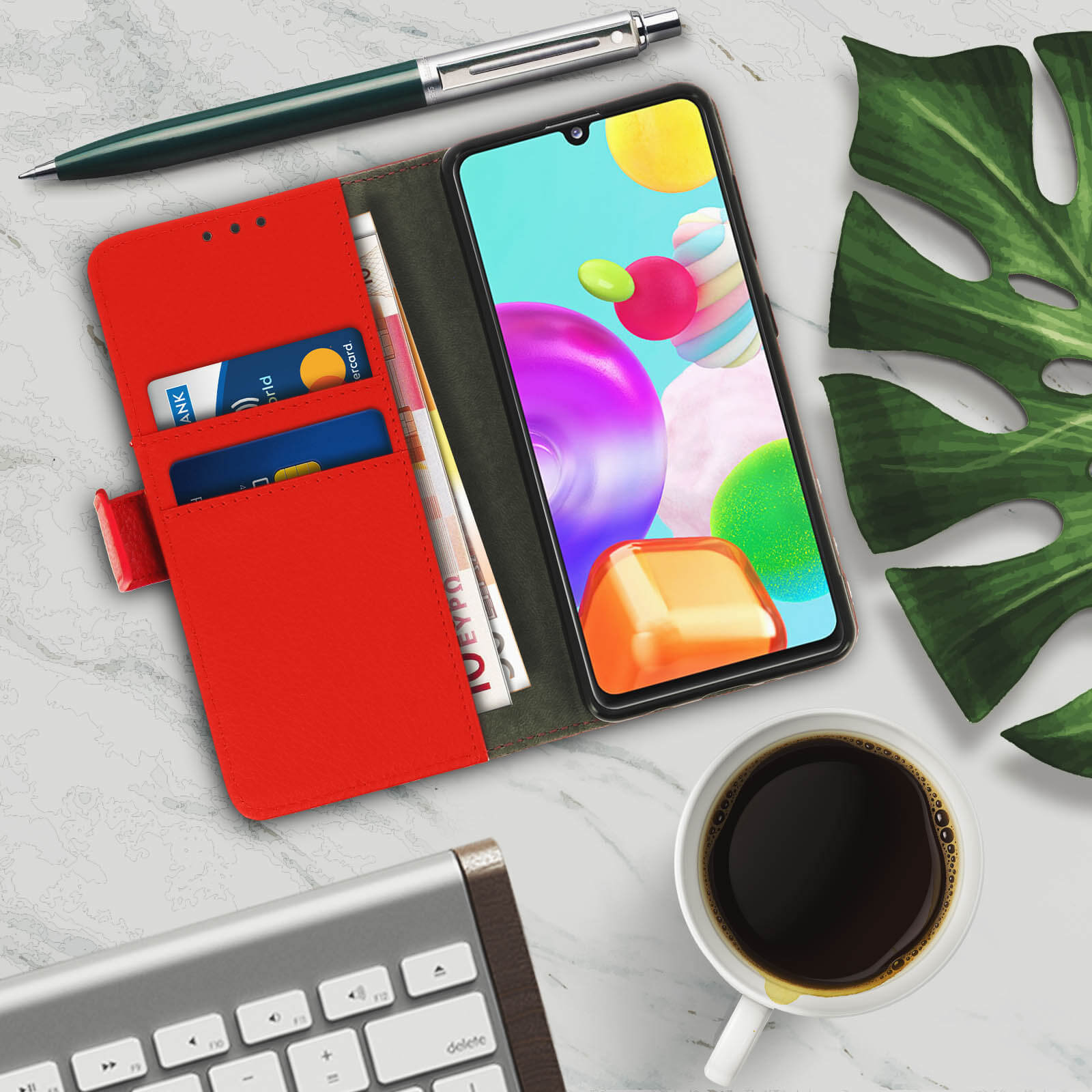 Étui de téléphone ouvert avec téléphone, cartes et argent. Café, clavier et stylo sont également visibles.