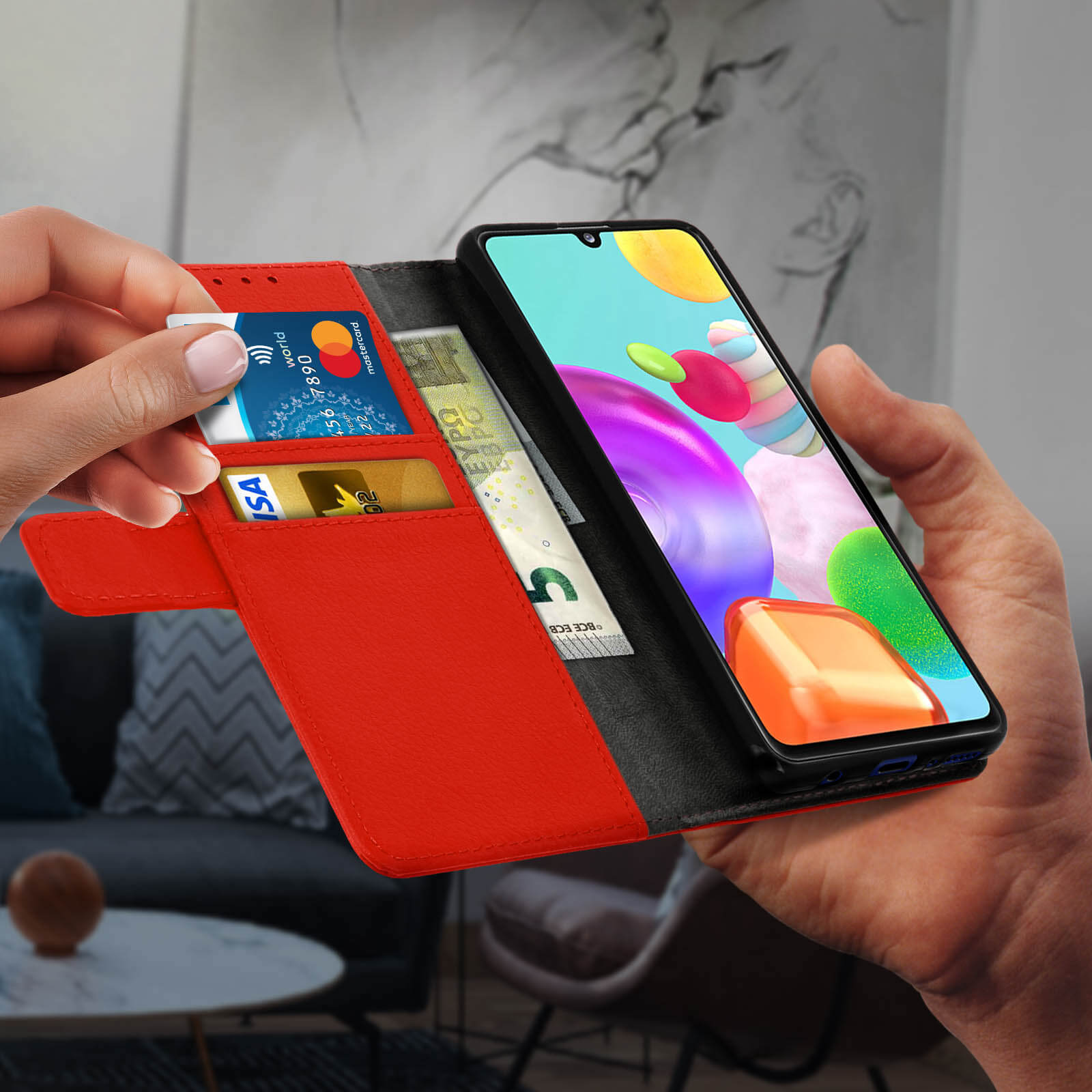 Un étui portefeuille rouge, avec un téléphone et des cartes à l'intérieur, est tenu par une main.