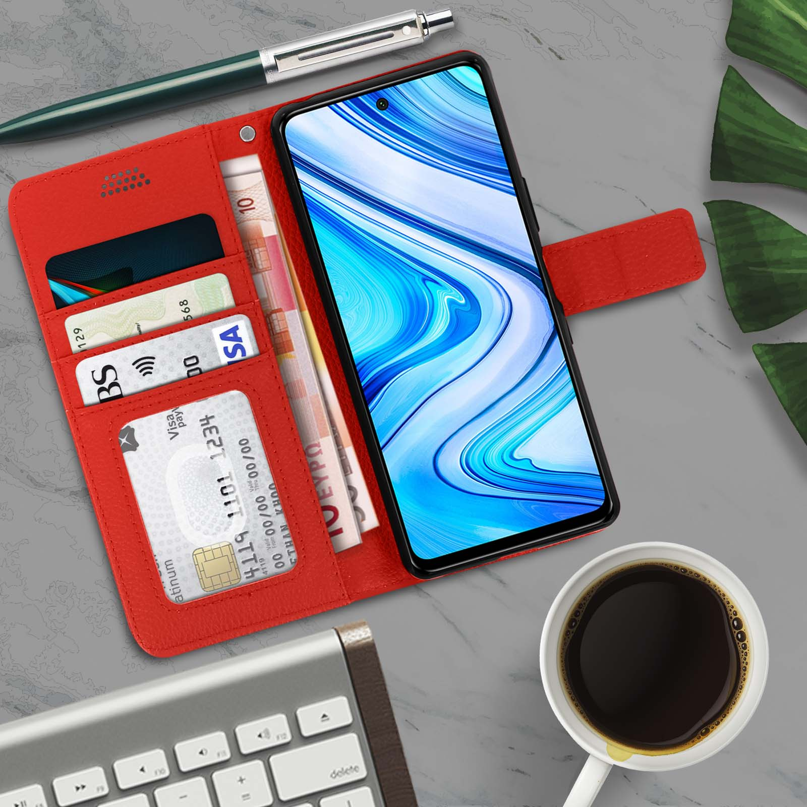 Rode telefoonhoes open. Binnenin kaarten en geld. Koffiekopje, toetsenbord op het oppervlak.