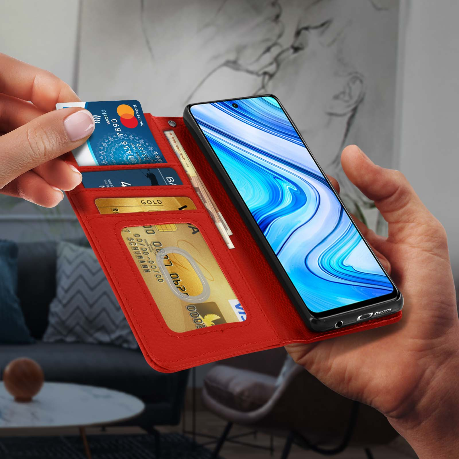 Rode telefoonportemonnee met creditcards en een telefoon. Hand die de portemonnee vasthoudt.