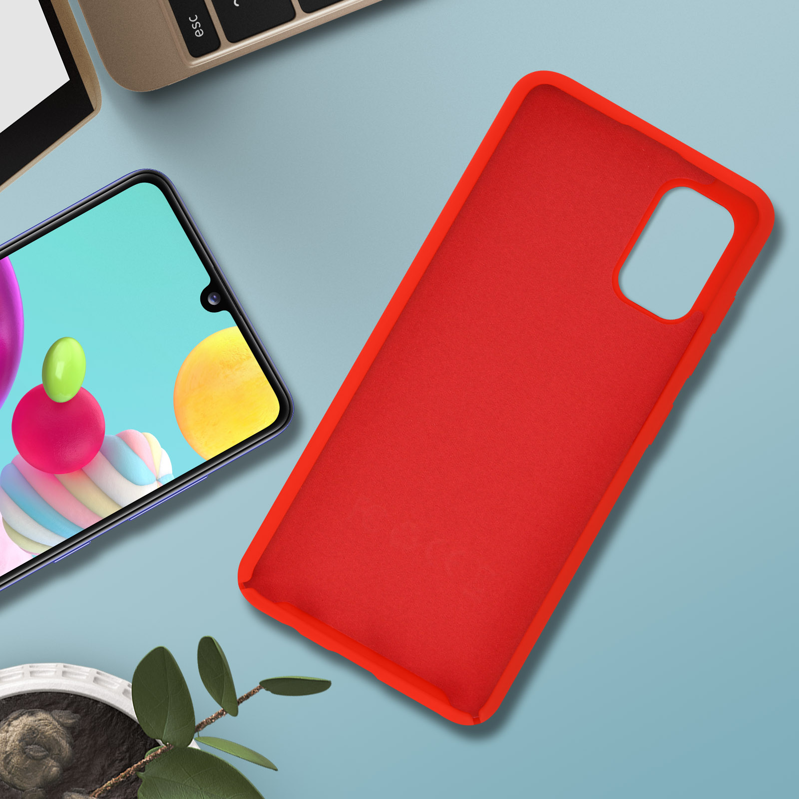 Een rode telefoonhoes en een telefoon op een blauw oppervlak. Een laptop is gedeeltelijk zichtbaar.